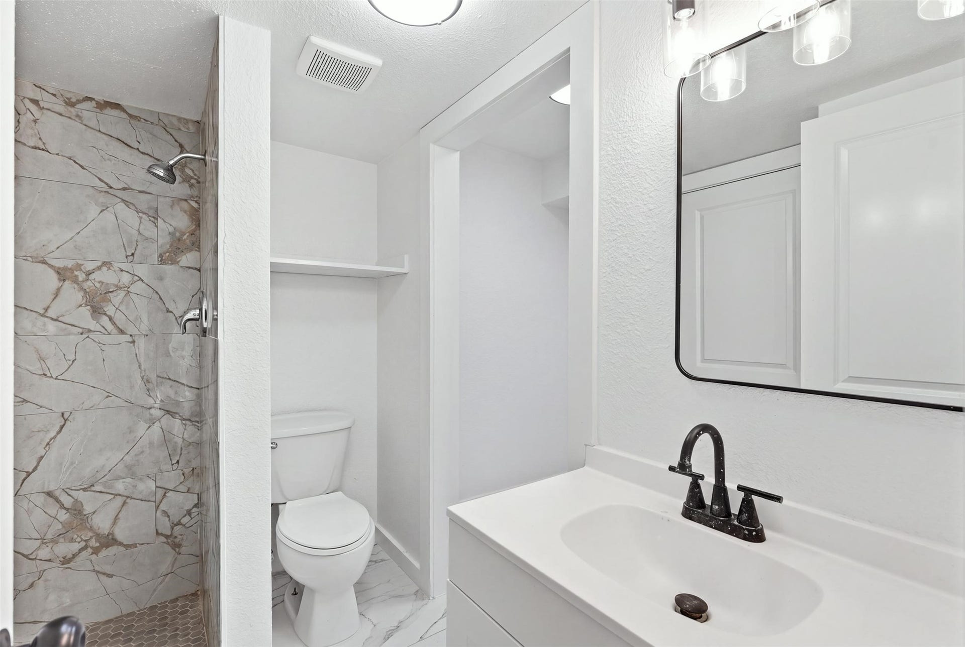 1936 Upland Drive, Houston, TX 77043 Elegant bathroom featuring a marble-tiled shower, modern fixtures, and a sleek vanity with ample storage.