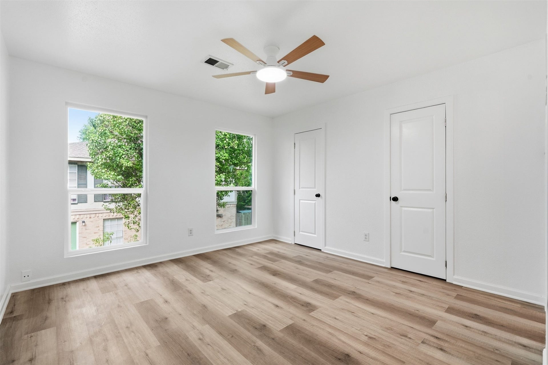 1936 Upland Drive, Houston, TX 77043 Bright and airy bedroom featuring large windows, sleek hardwood floors, and a modern ceiling fan, offering a serene retreat.