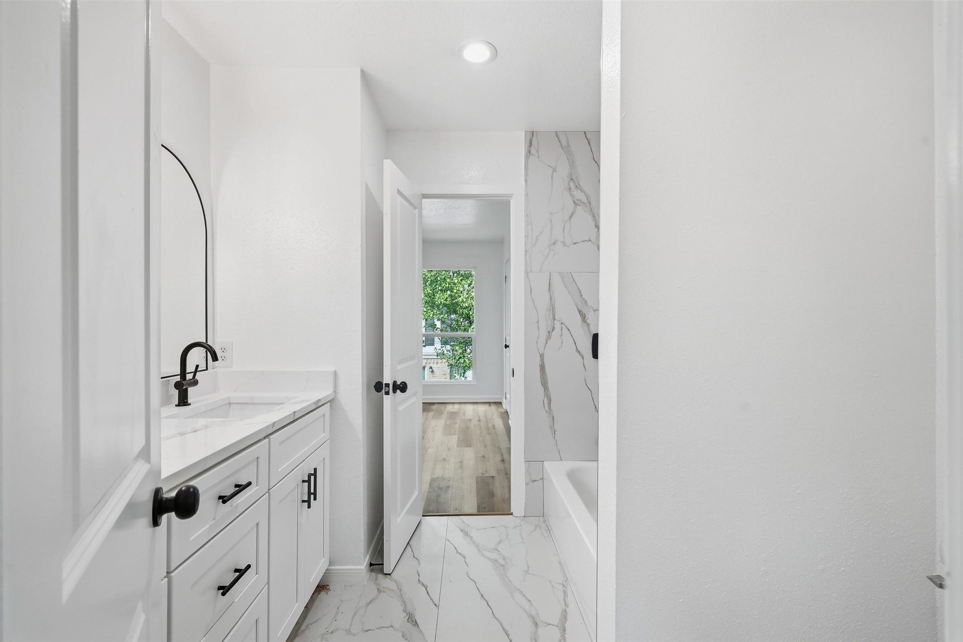 1936 Upland Drive, Houston, TX 77043 Modern bathroom featuring sleek white cabinetry, elegant marble-like tile flooring, and a stylish black faucet.