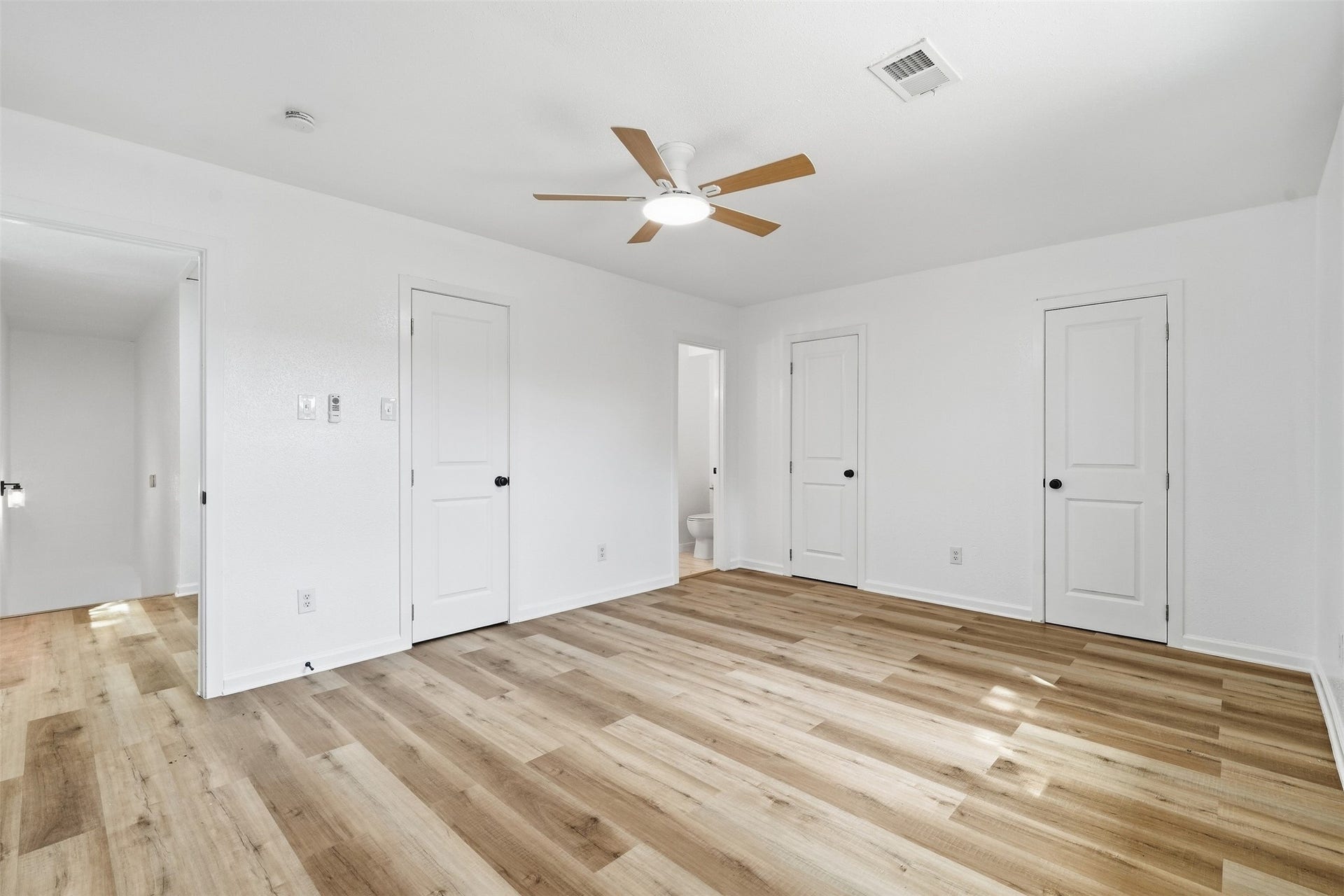 1936 Upland Drive, Houston, TX 77043 Spacious bedroom featuring fresh white walls, elegant wood-look flooring, and a modern ceiling fan, creating a bright and inviting atmosphere.