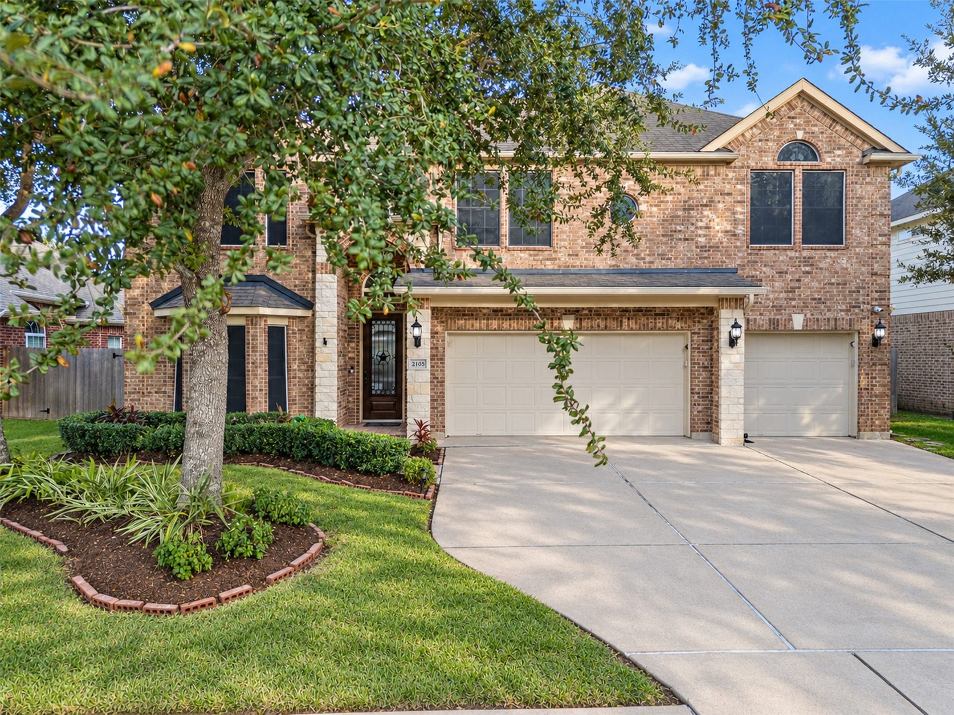 Beautiful two-story brick home featuring a welcoming entry, attractive landscaping, and a three-car garage.