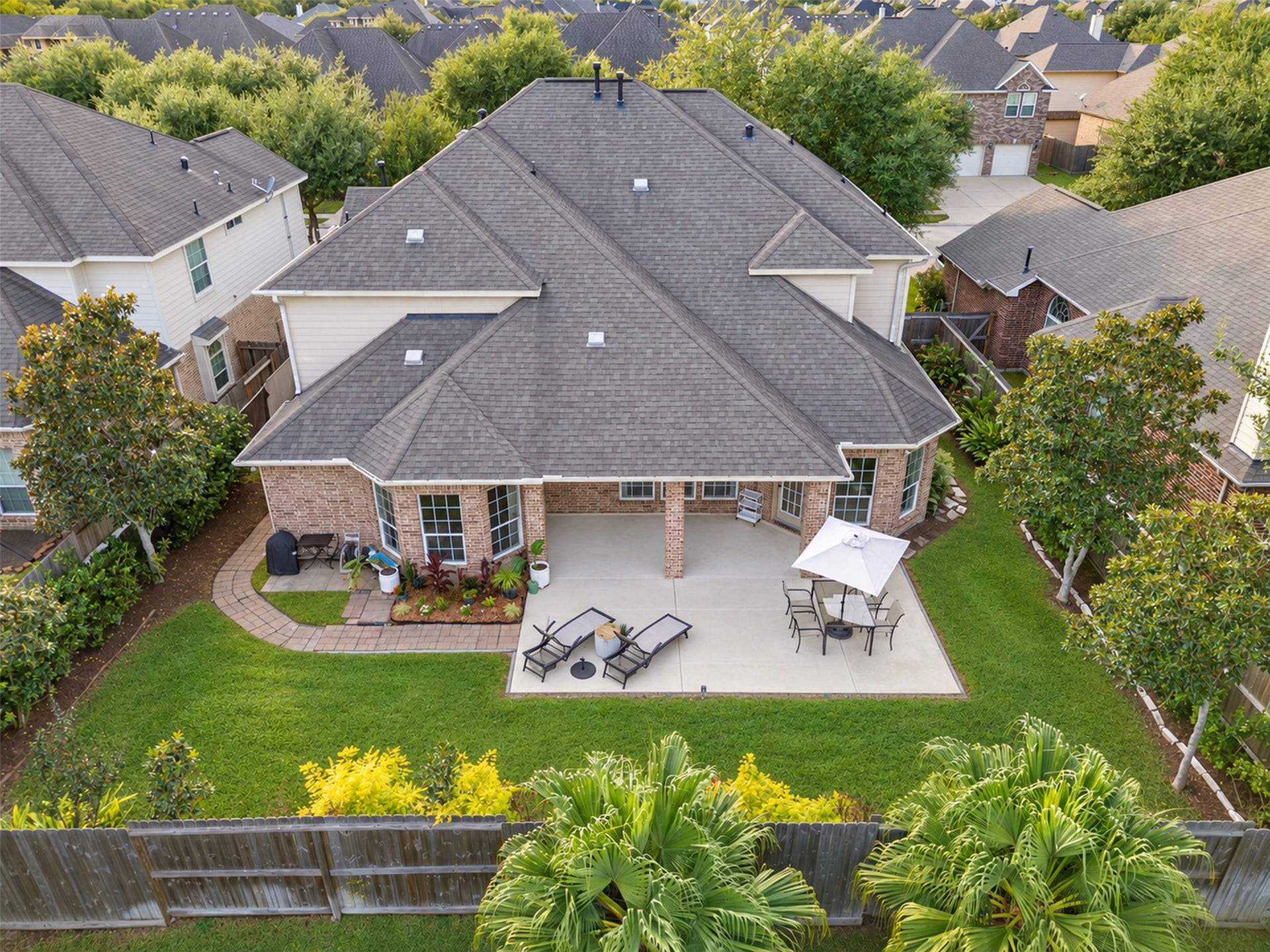 Bird's-eye view highlighting the spacious covered patio, extended outdoor entertaining area, and beautifully landscaped backyard.