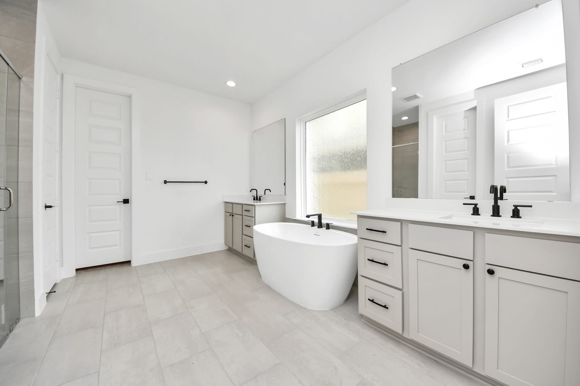 5914 Fox Peak Lane, Richmond, TX 77469 Escape to a spa-like oasis in this primary bathroom. Enjoy a walk-in shower with tile surround, a separate garden tub with custom detailing, and an elegant vanity featuring light countertops, modern hardware, and beautiful recessed lights. Experience luxury and relaxation in every detail. Sample photo of completed home with similar floor plan. Actual colors and selections may vary.