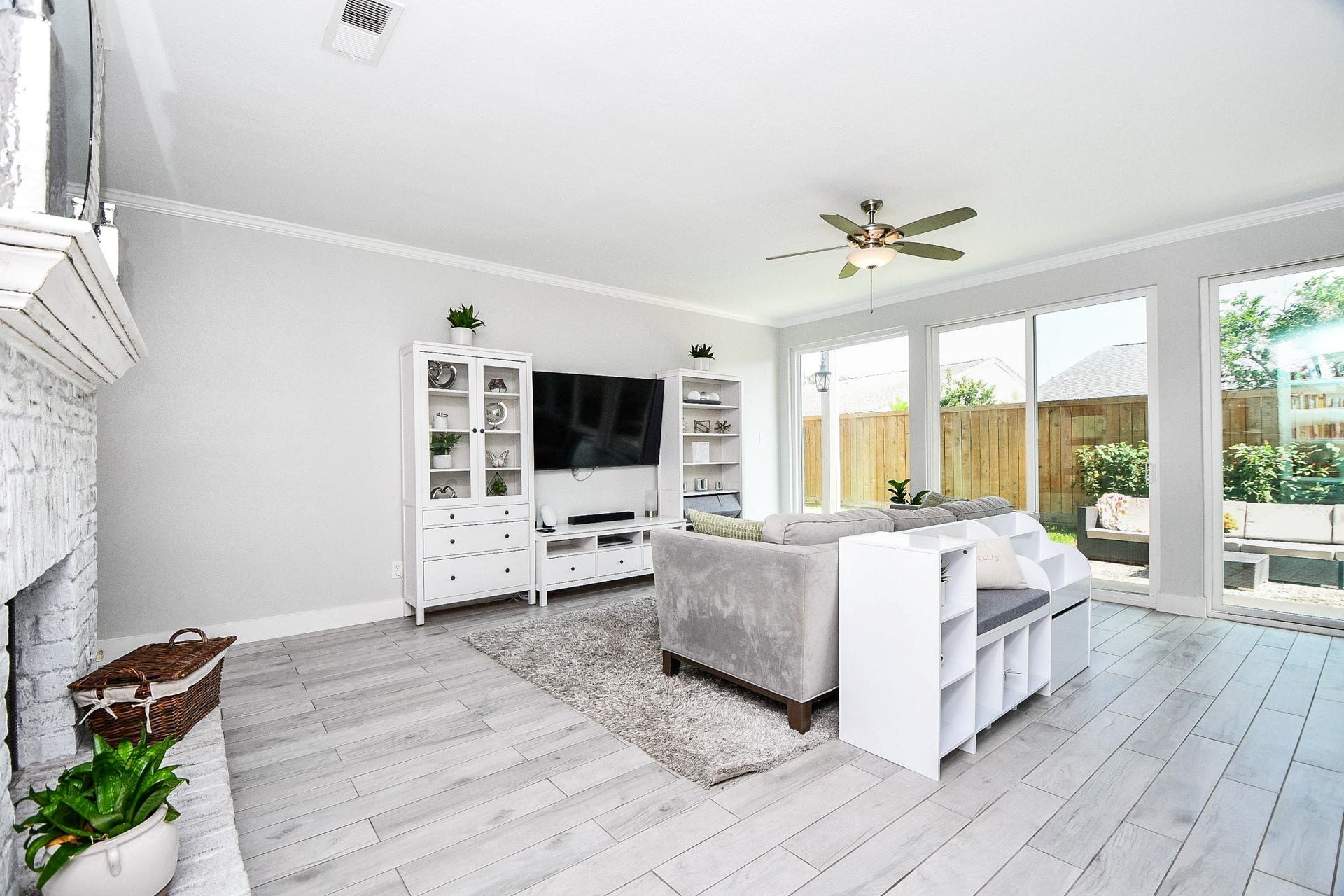 811 Bayou River Drive, Houston, TX 77079 The living room has wood-look tile floors, a ceiling fan, and backyard views.