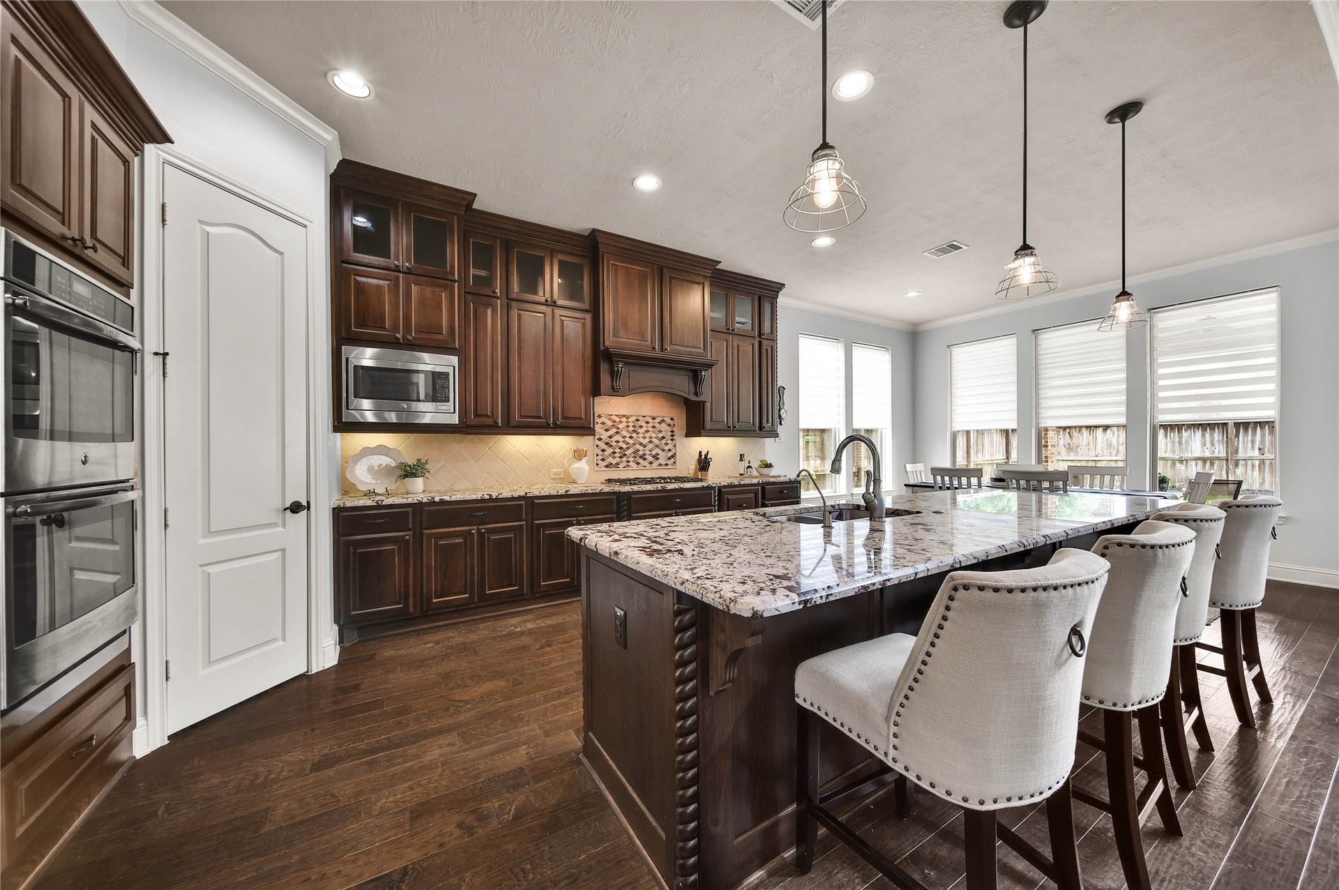 27707 Lakeway Trail Lane, Fulshear, TX 77441 The cabinetry and detailed trim work throughout the kitchen are simply beautiful, adding a touch of elegance and craftsmanship to the space. The cabinets extend all the way to the ceiling, featuring glass-front doors across the top row for a sophisticated display and elevated design.