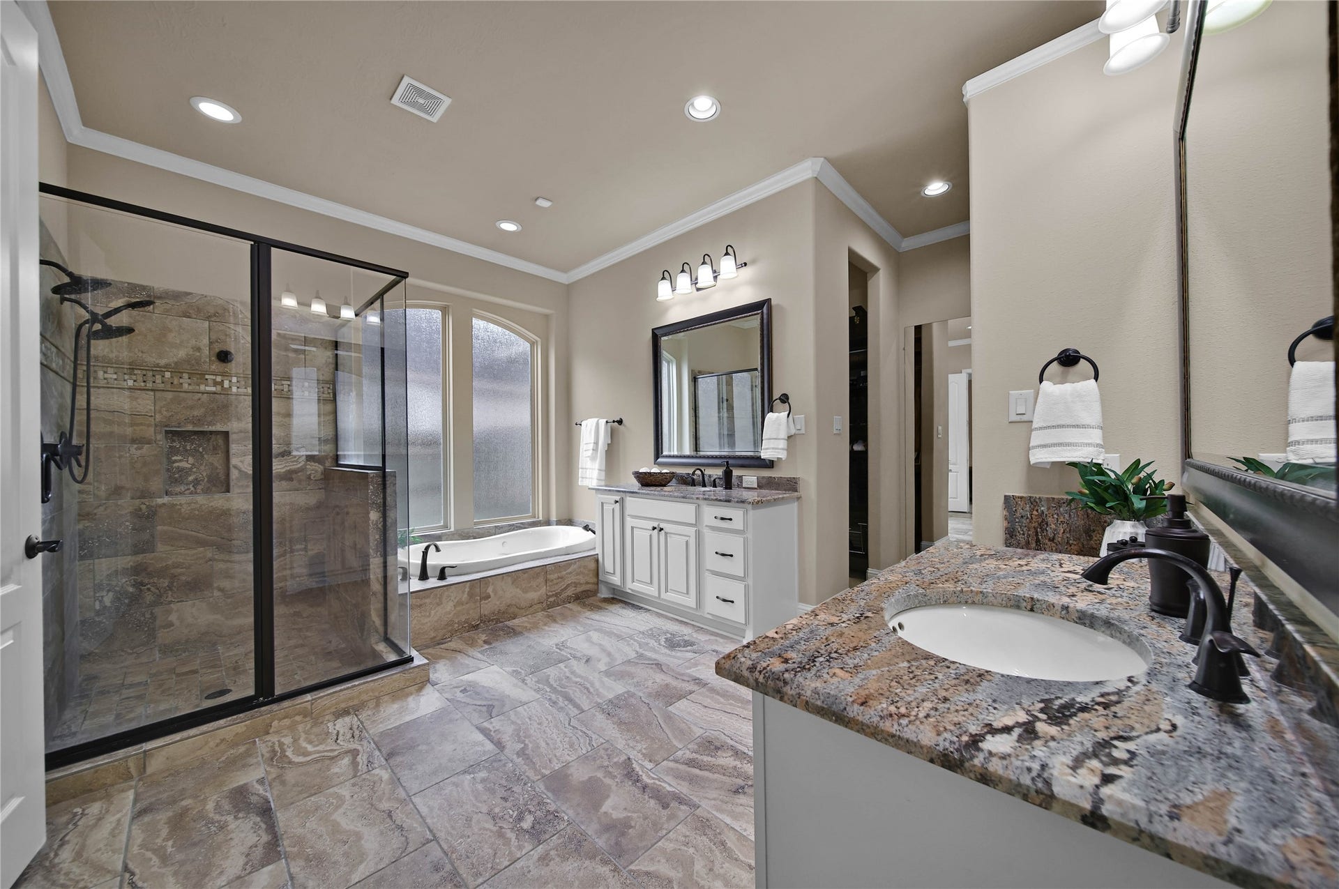 27707 Lakeway Trail Lane, Fulshear, TX 77441 Neutral colors and natural materials add subtle elegance to the primary bath.The space is thoughtfully designed with a dedicated dressing mirror and two spacious closets featuring custom built-ins for exceptional organization and convenience.