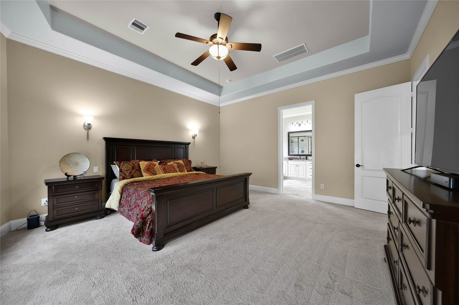 27707 Lakeway Trail Lane, Fulshear, TX 77441 The primary suite features a beautiful tray ceiling with elegant lighting sconces and opens to a luxurious bath, creating a relaxing retreat to unwind at the end of the day.