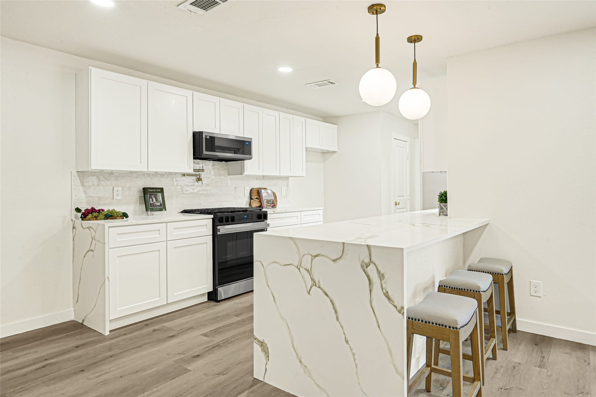 11102 Sagecanyon Drive, Houston, TX 77089 Beautifully remodeled kitchen featuring quartz countertops with waterfall-style island, white shaker cabinetry, stylish brushed gold accents, and modern pendant lighting. Perfect for cooking and entertaining!