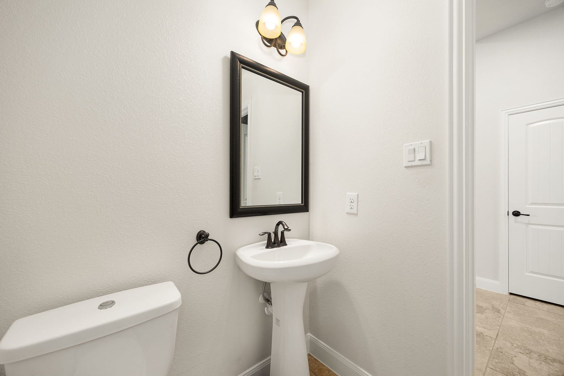 9931 Hutton Park Drive, Katy, TX 77494 A crisp, clean powder room offers convenience for guests with a classic pedestal sink and modern dark-trimmed fixtures. The neutral color palette and bright lighting create a welcoming, airy feel right off the main living areas.