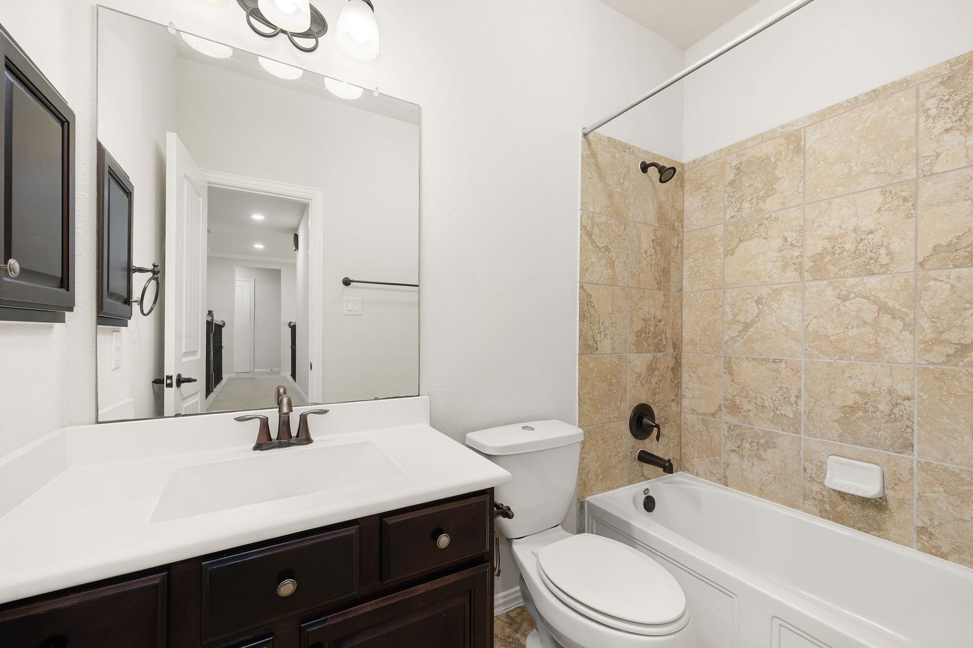 9931 Hutton Park Drive, Katy, TX 77494 This bright secondary bathroom features a cohesive design with a dark wood vanity, a crisp white countertop, and oil-rubbed bronze fixtures. The tub-and-shower combination is beautifully finished with warm neutral tile surround, matching the polished look found throughout the home.