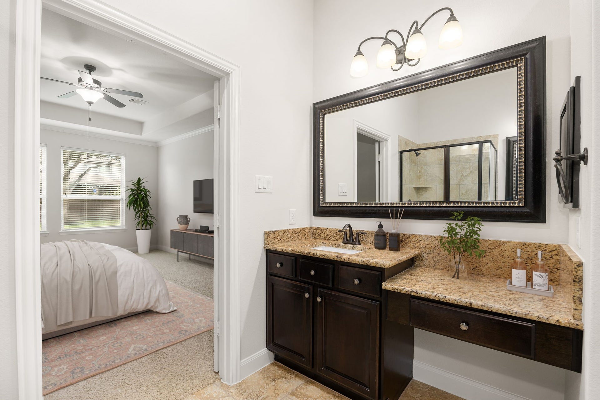9931 Hutton Park Drive, Katy, TX 77494 This elegant space features rich custom cabinetry with ample storage, paired beautifully with a dedicated makeup vanity niche. A grand, dark-framed mirror anchors the wall, highlighted by upscale light fixtures and natural stone countertops that elevate the home's sophisticated design.