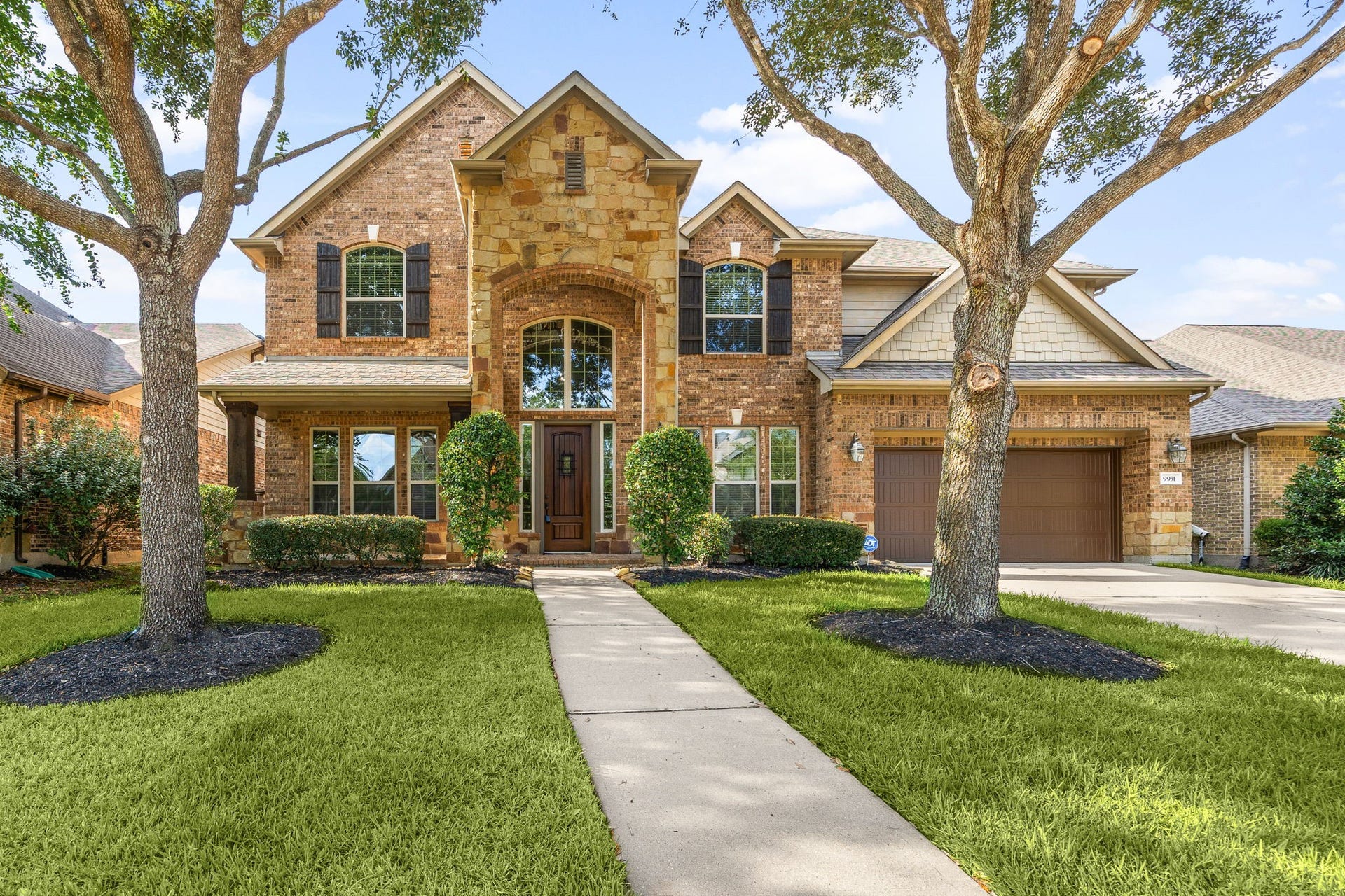 9931 Hutton Park Drive, Katy, TX 77494 Welcome home to 9931 Hutton Park Drive, located on a quiet street in Cinco Ranch Southwest and zoned to Katy ISD! This charming home offers timeless curb appeal with a well-manicured lawn, mature trees, and classic brick-and-stone elevation. A dark-stained front door with glass detailing, covered front porch, coordinating shutters, beautiful outdoor lanterns, and double-wide driveway complete the inviting exterior.
