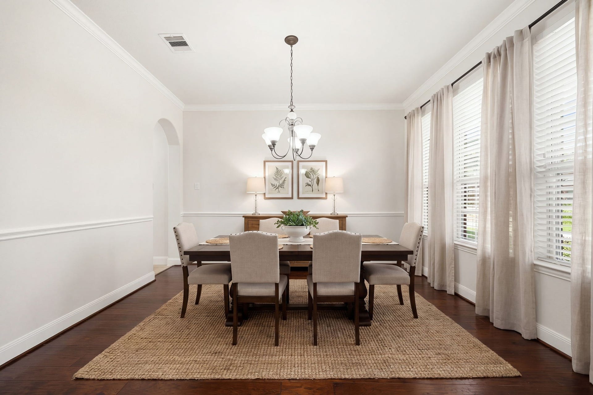 9931 Hutton Park Drive, Katy, TX 77494 This elegant space features classic wainscoting and crisp crown molding that beautifully contrast with rich, dark hardwood floors. A striking central chandelier serves as a sophisticated focal point, while a large wall of windows brings in gentle, diffused natural light to create an inviting atmosphere for formal hosting.