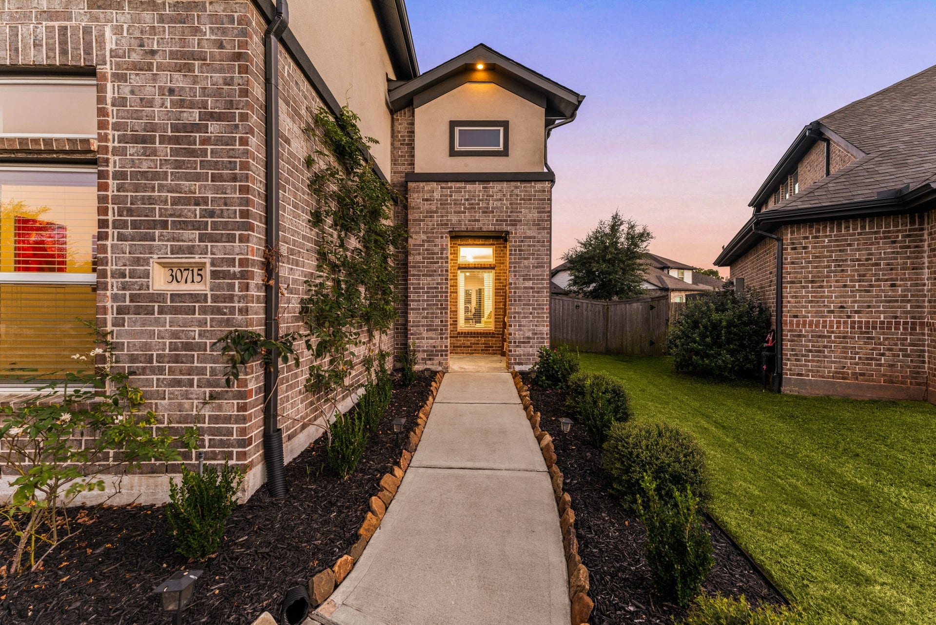 30715 Parkside Passage Drive, Fulshear, TX 77441 A welcoming and beautifully pathway greets you as you approach this gorgeous home. The exterior showcases timeless four-sided brick construction paired with dark architectural trim and clean stucco accents above. The details of this home exudes exceptional curb appeal.