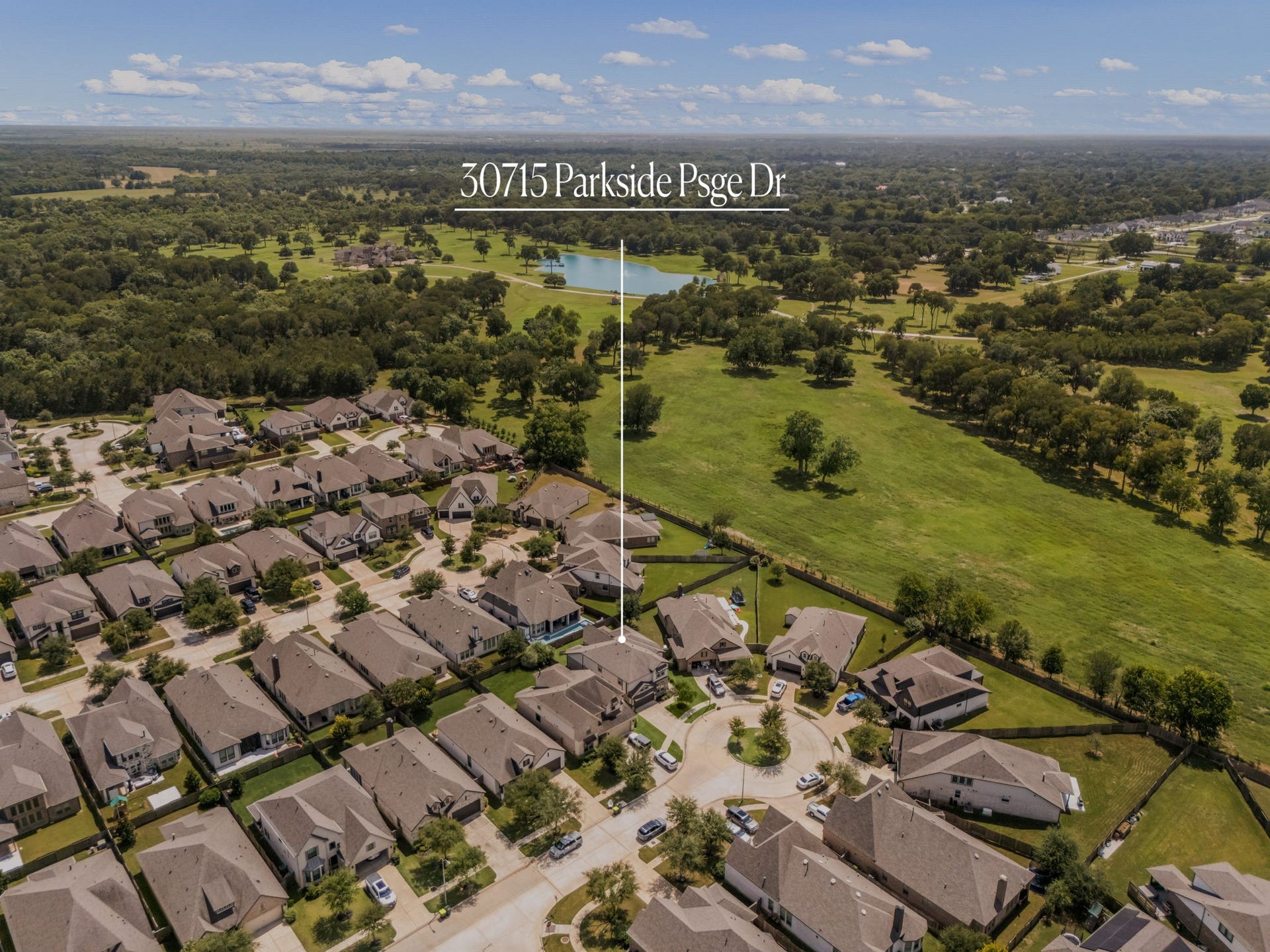 30715 Parkside Passage Drive, Fulshear, TX 77441 Nestled along a quiet, tree-lined cul-de-sac street, the home features a premium oversized lot that backs directly up to a massive, beautifully preserved greenbelt area. This extensive green space offers panoramic views of mature trees, rolling lawns, and a scenic neighborhood lake just beyond the property line.