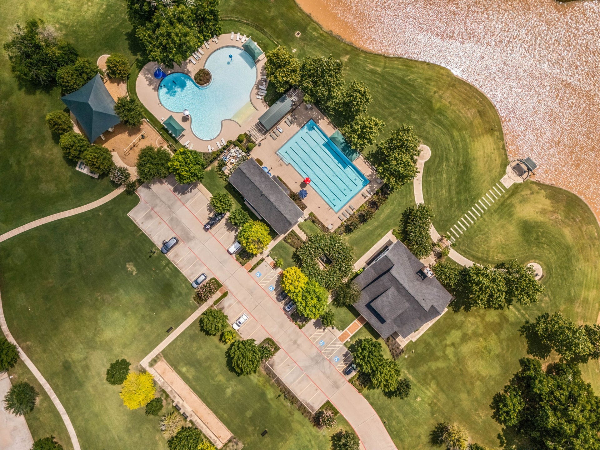 30715 Parkside Passage Drive, Fulshear, TX 77441 An aerial view of the stunning Fulbrook on Fulshear Creek amenity center, featuring a massive resort-style pool, a dedicated multi-lane competition pool, a playground, and a lakeside lodge. Enjoy a vacation vibe every day right inside your own neighborhood!