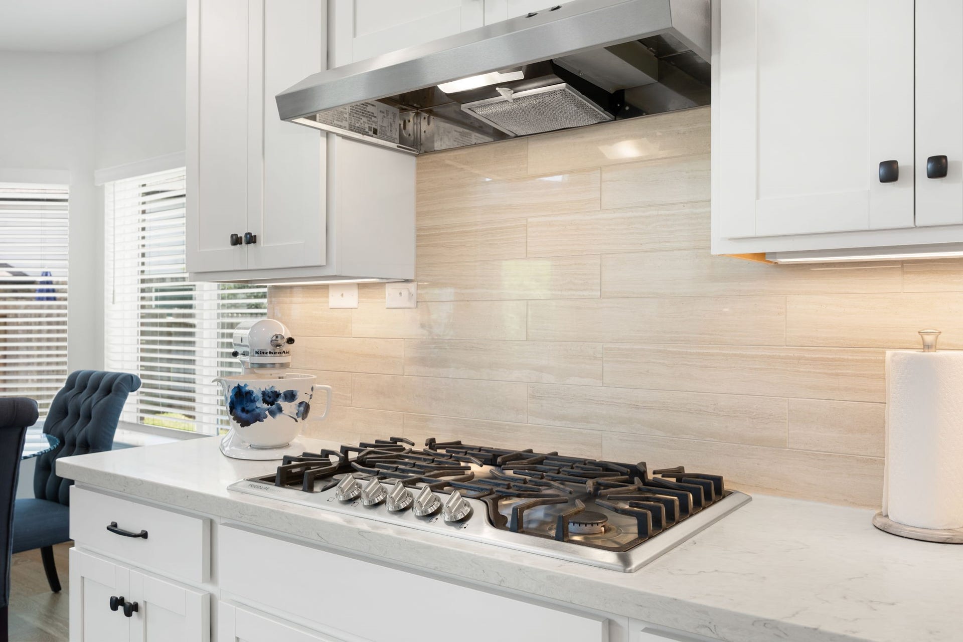 30715 Parkside Passage Drive, Fulshear, TX 77441 Featured here is the high-end, five-burner gas cooktop integrated seamlessly into the quartz countertops. Overhead, a professional-grade stainless steel vent hood provides powerful ventilation and integrated lighting.