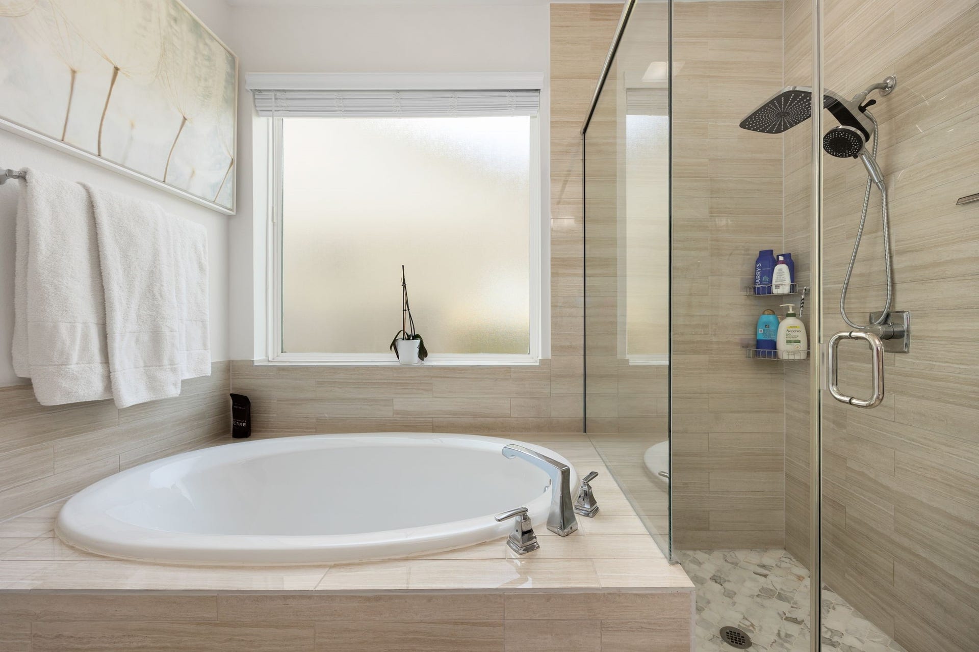 30715 Parkside Passage Drive, Fulshear, TX 77441 A closer view of the primary en-suite highlights the luxurious deep soaking tub and adjacent walk-in shower. The expansive shower is enclosed by seamless glass panels and features elegant linear tile walls, a decorative pebble-tile floor, and a premium multi-function showerhead. A large frosted-glass window sits directly above the soaking tub, filling the entire space with natural light and privacy.