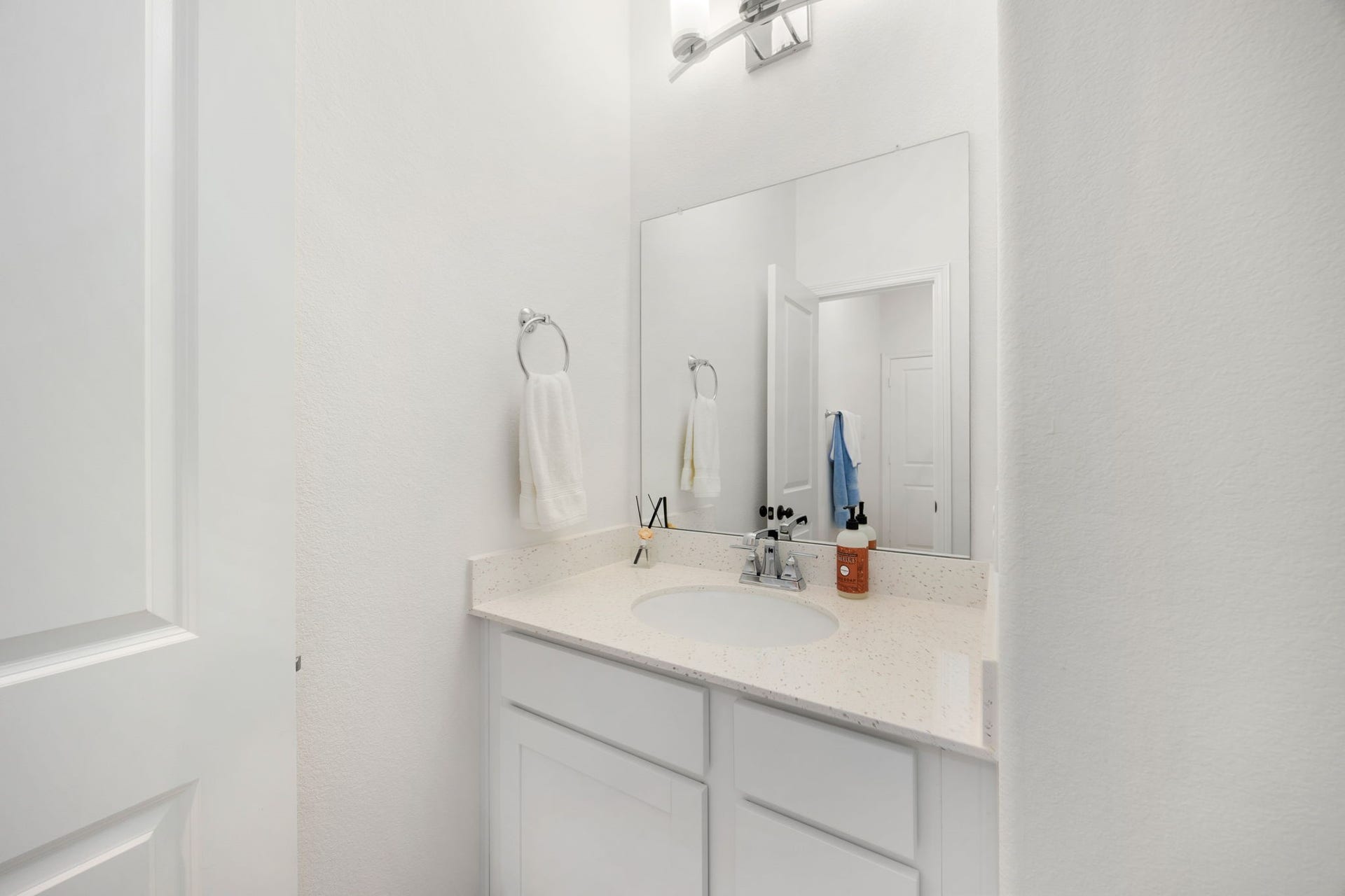 30715 Parkside Passage Drive, Fulshear, TX 77441 A private, dedicated vanity alcove serves the secondary bedroom, offering an ideal layout that mirrors the style of a traditional Hollywood bathroom configuration. This practical setup features a clean white vanity cabinet with seamless storage, a neutral solid-surface countertop with an undermount sink, and a large frameless mirror.