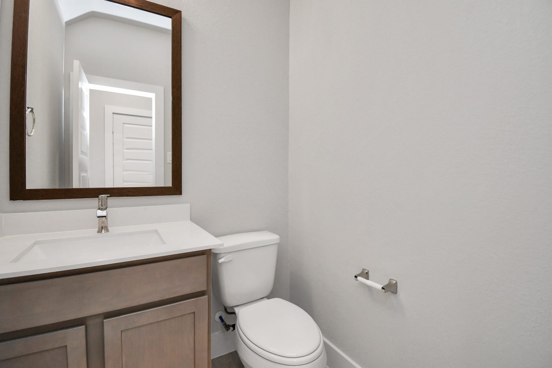 Delightful half bathroom featuring a sophisticated 5-panel door, upgraded sink, contemporary hardware, and bright recessed lights. Sample photo of completed home with similar floor plan. Actual colors and selections may vary.