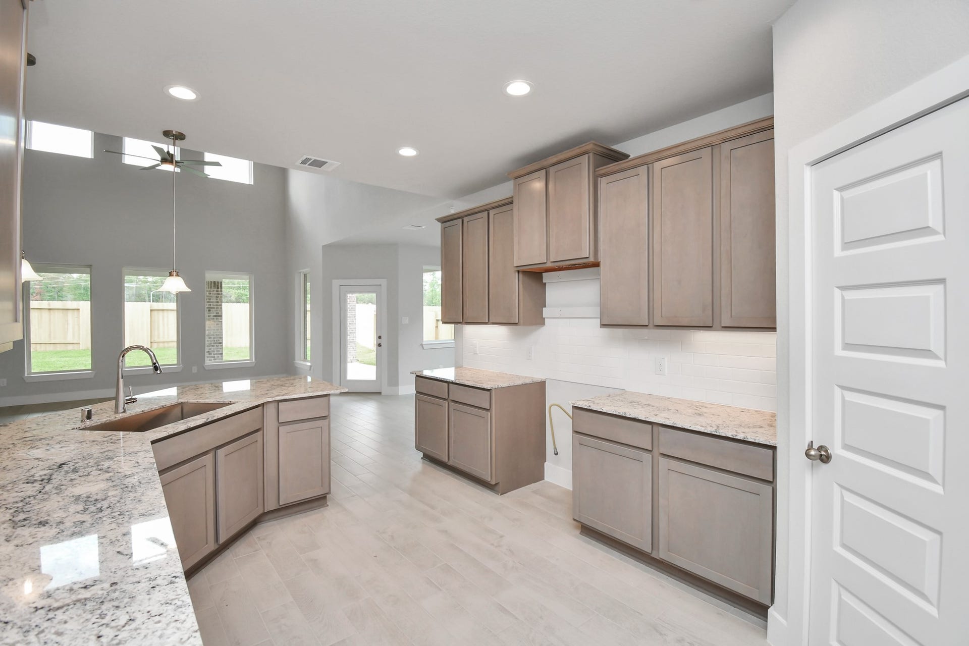 This kitchen is by far any chefs dream! This spacious kitchen features high ceilings, stained wood cabinets, granite countertop, SS appliances, modern tile backsplash, recessed lighting, and an extended counter space. Sample photo of completed home with similar floor plan. Actual colors and selections may vary.