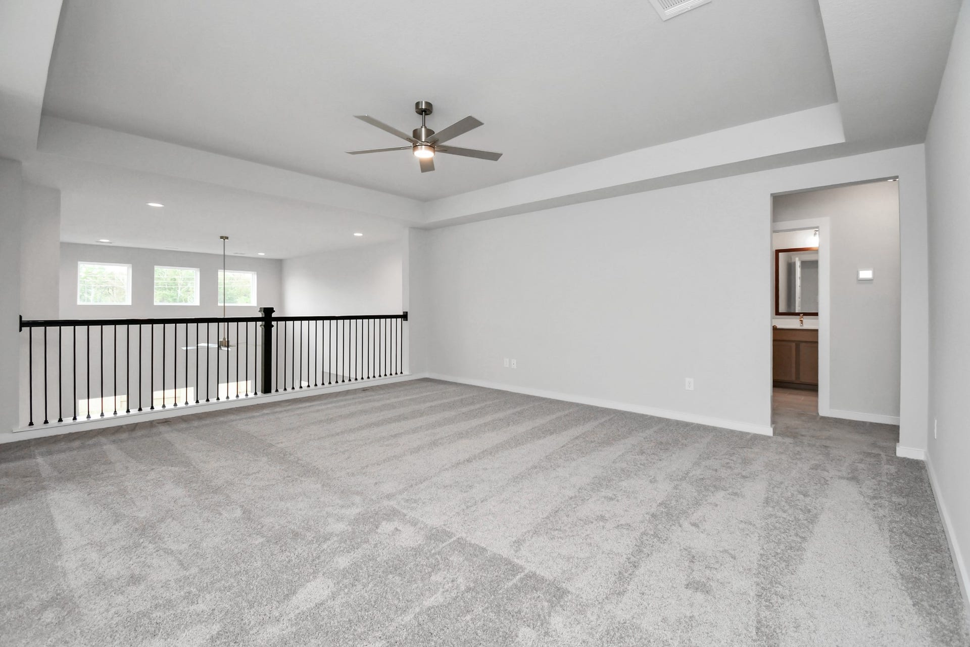 Discover a haven of leisure in this fantastic game room! Whether you're seeking a casual hangout or an adult gaming retreat, this space has it all. Enjoy the luxurious feel of plush carpet underfoot, the expansive ambiance of high ceilings, custom paint that adds a touch of personality, and windows that flood the room with refreshing natural light. Sample photo of completed home with similar floor plan. Actual colors and selections may vary.