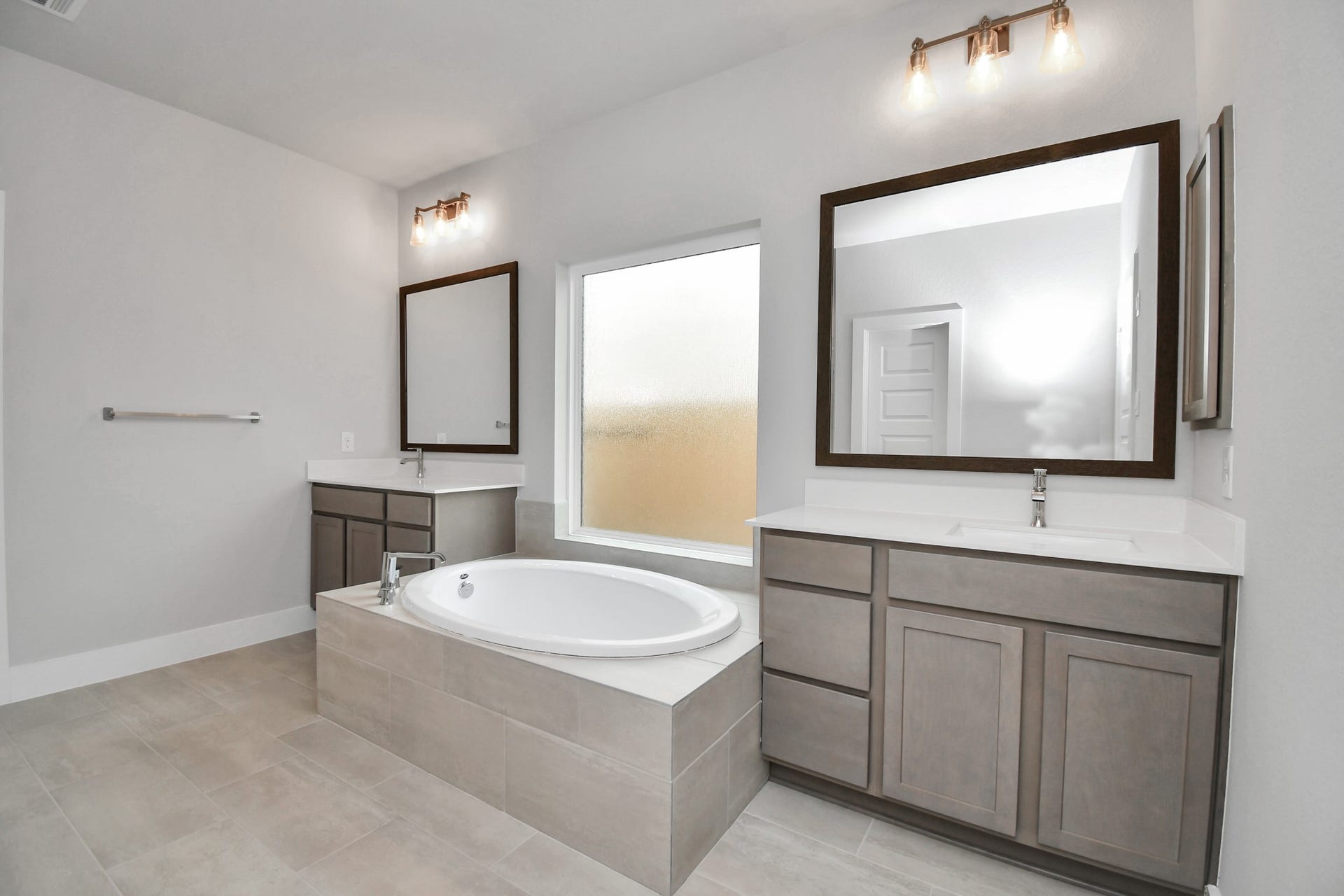 Indulge in a spa-like retreat within the confines of this primary bathroom. Delight in a spacious walk-in shower enveloped in stylish tile surround and unwind in a separate garden tub adorned with custom detailing. Sample photo of completed home with similar floor plan. Actual colors and selections may vary.
