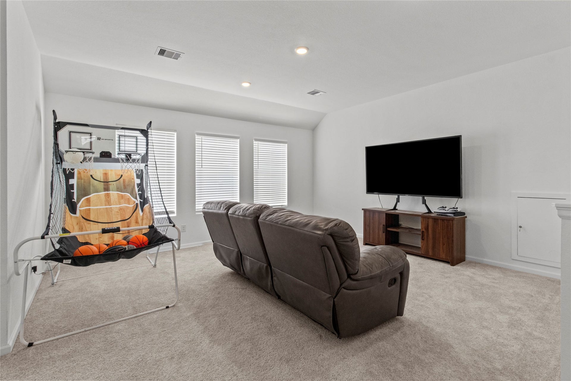 2909 Ballast Green Drive, La Marque, TX 77568 Spacious entertainment room featuring comfortable seating, a large TV, and an indoor basketball game, perfect for family fun and relaxation.