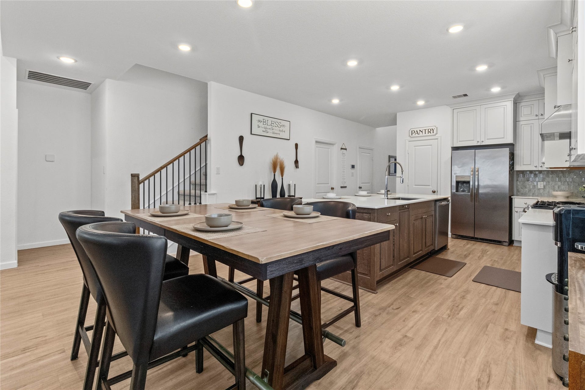 2909 Ballast Green Drive, La Marque, TX 77568 Bright and modern kitchen featuring a large center island with a farmhouse sink, sleek stainless steel appliances, and ample cabinetry, complemented by a stylish dining area with contemporary seating.