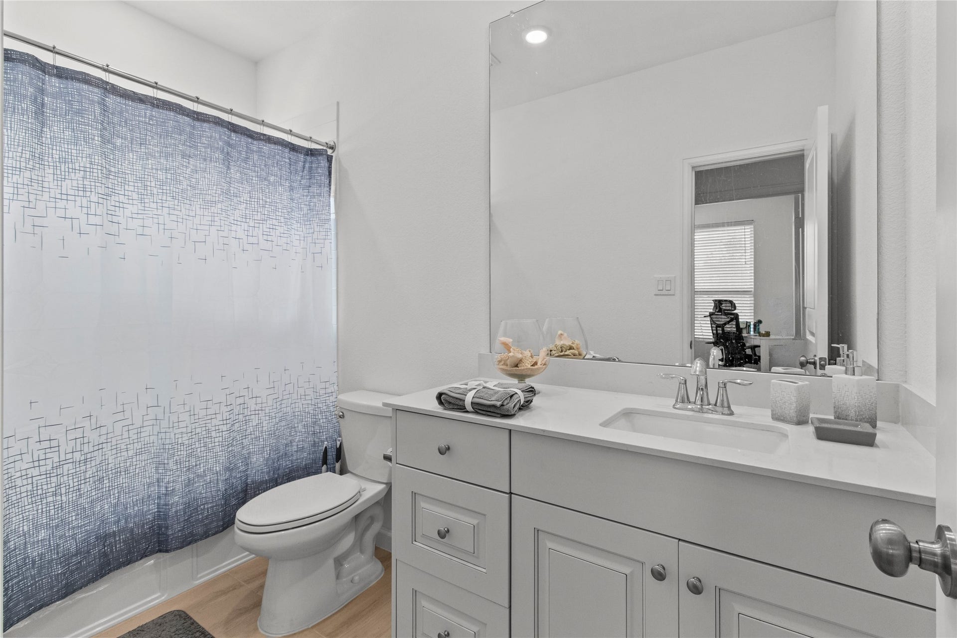 2909 Ballast Green Drive, La Marque, TX 77568 Bright and modern bathroom featuring a sleek vanity with ample storage, a large mirror, and a stylish shower curtain accentuating the space.