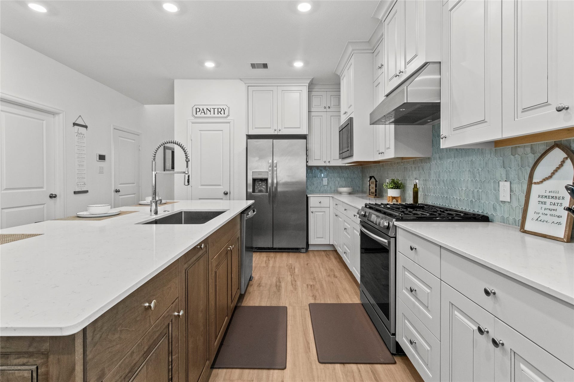 2909 Ballast Green Drive, La Marque, TX 77568 Sleek kitchen featuring a spacious island with a modern sink, stainless steel appliances, and ample cabinet space. The elegant backsplash and wood flooring add a warm touch to this inviting culinary space.