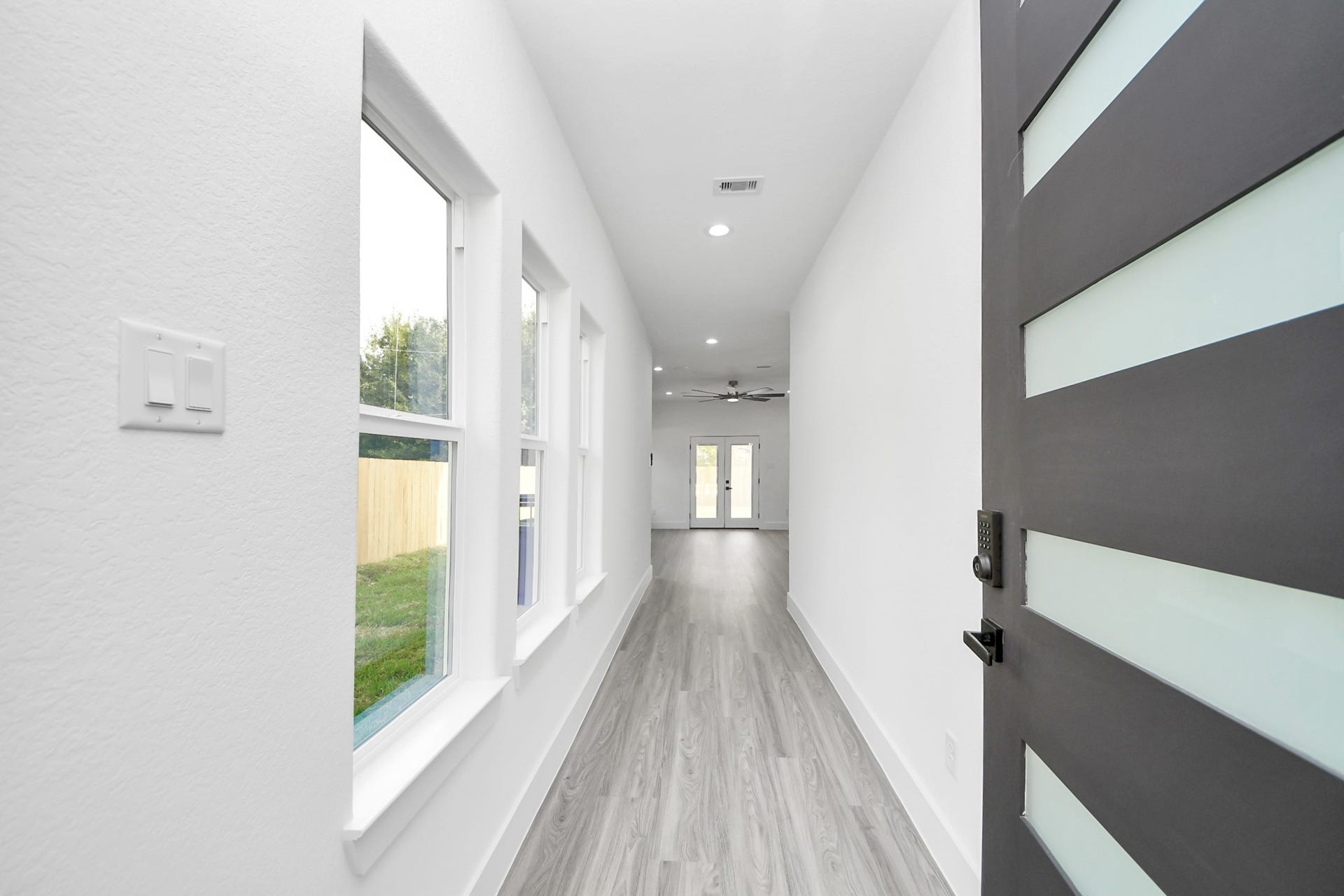6711 Crestmont Street, Houston, TX 77033 Sleek entryway with modern door and abundant natural light, leading to an open living space with stylish flooring.