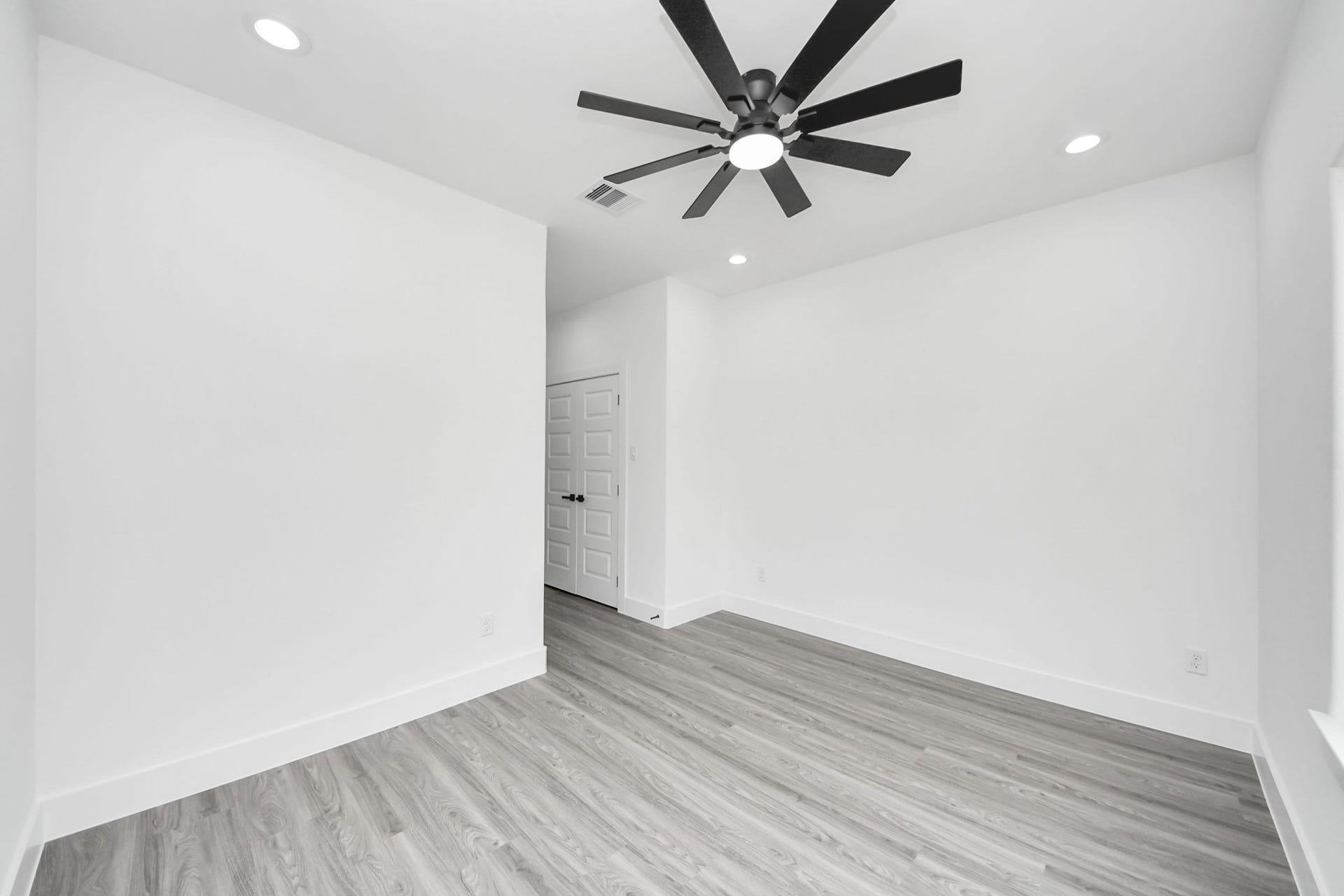 6711 Crestmont Street, Houston, TX 77033 Bright, minimalist room featuring sleek wood flooring, recessed lighting, and a modern ceiling fan, perfect for a cozy and functional living space.