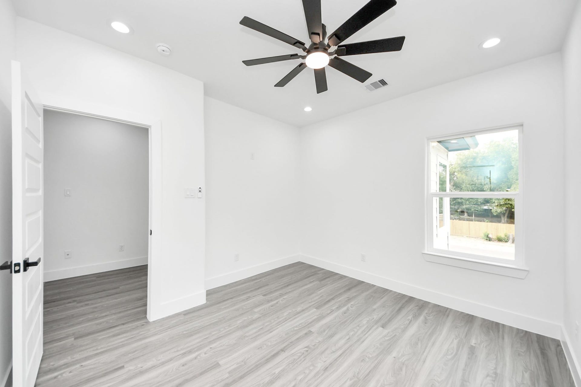 6711 Crestmont Street, Houston, TX 77033 Bright and airy room featuring sleek hardwood floors, a modern ceiling fan, and ample natural light from a large window.