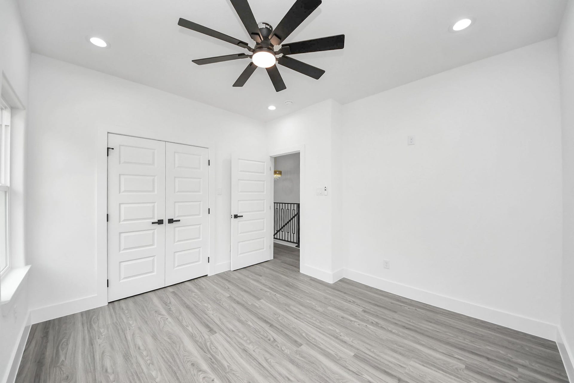 6711 Crestmont Street, Houston, TX 77033 Bright and airy room featuring sleek wood flooring, modern recessed lighting, and a stylish ceiling fan, complemented by double doors for added charm.