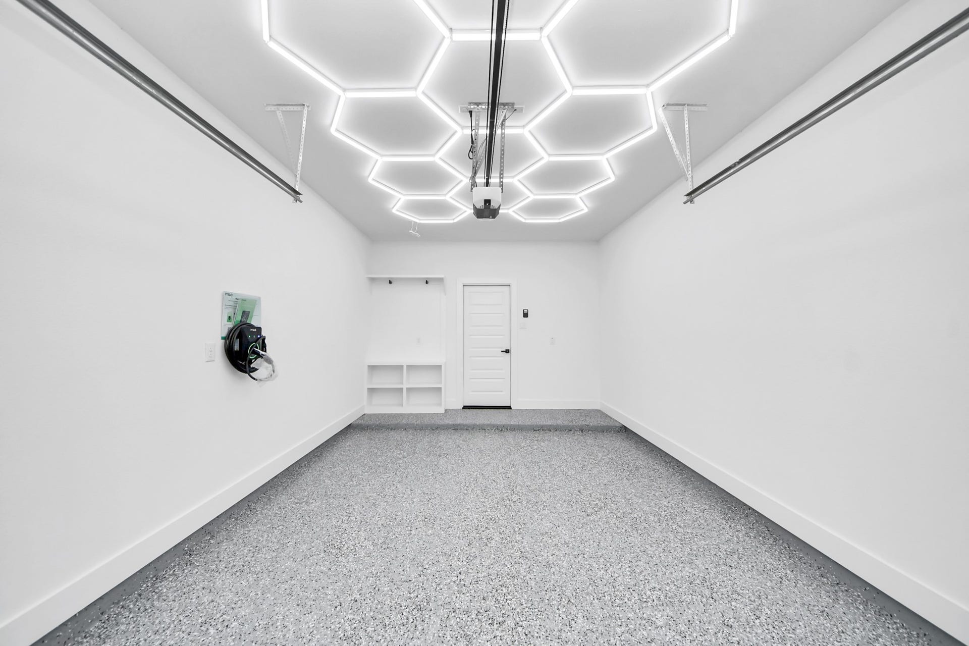 6711 Crestmont Street, Houston, TX 77033 A sleek, modern garage featuring hexagonal LED lighting, pristine white walls, and an epoxy-coated floor, offering both style and functionality.