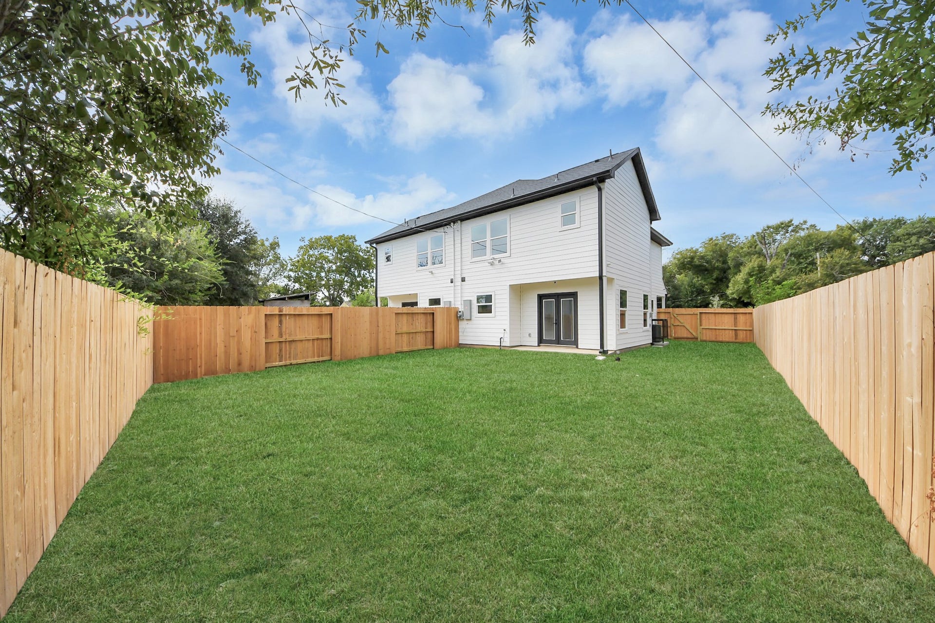 6711 Crestmont Street, Houston, TX 77033 Spacious backyard with lush green lawn, enclosed by a wooden fence, ideal for outdoor activities and privacy.