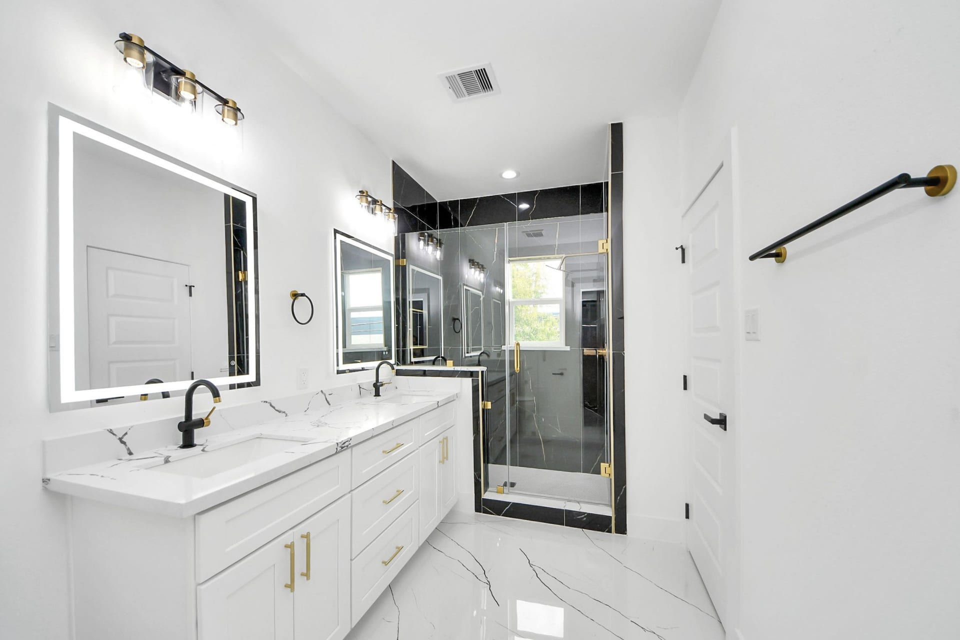 6711 Crestmont Street, Houston, TX 77033 Elegant bathroom featuring a double vanity with sleek black fixtures, luxurious marble countertops, and a spacious glass-enclosed shower with gold accents.