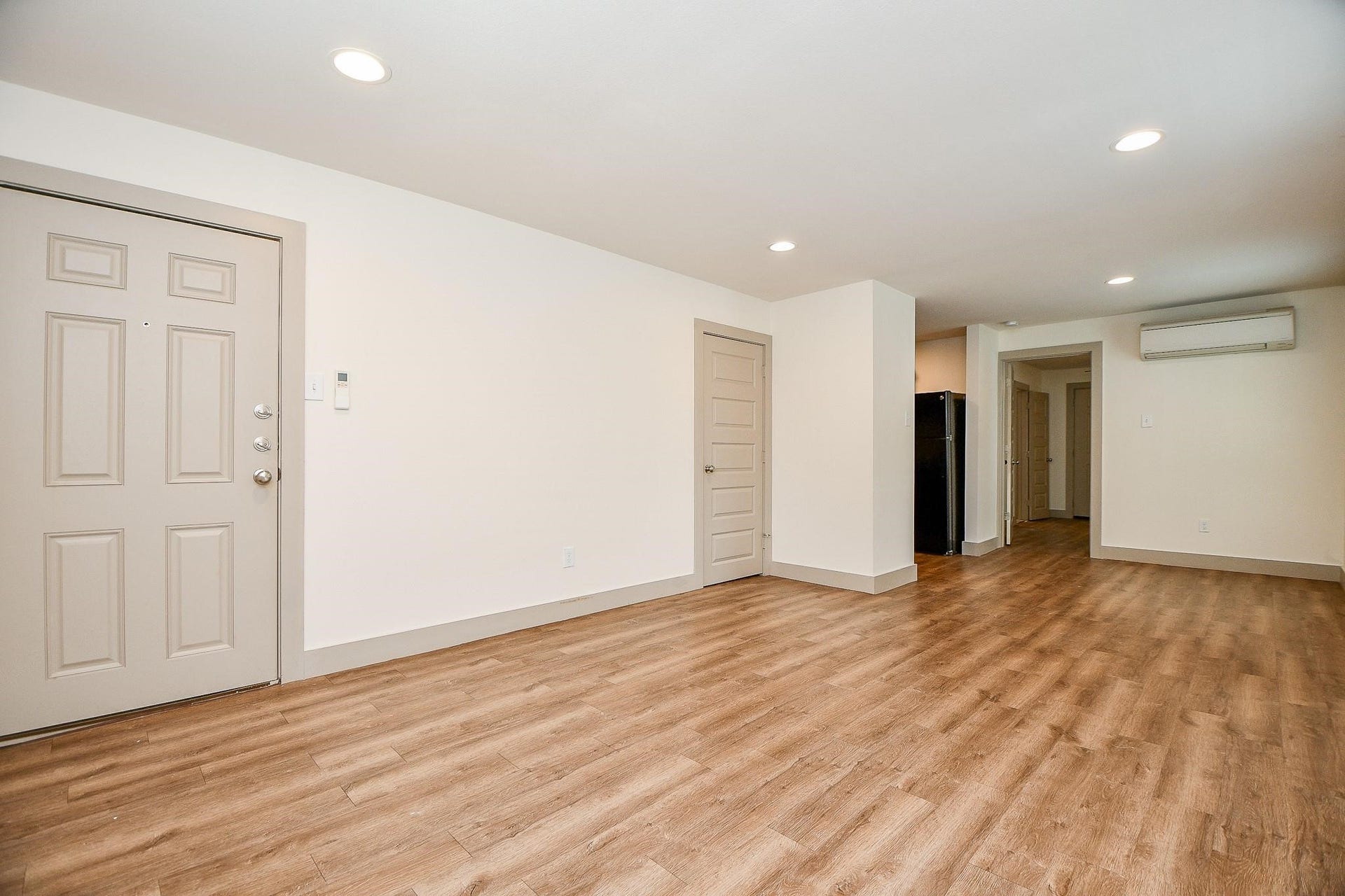 Spacious, open layout with light wood type flooring and neutral walls.