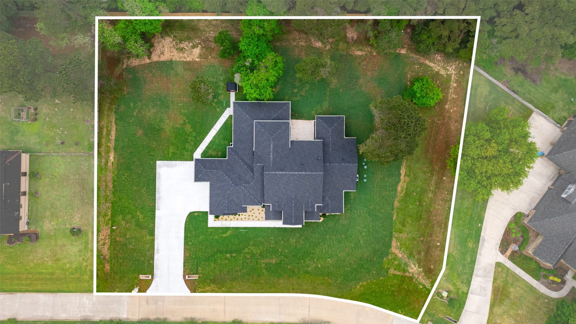 22420 Meadowhurst Circle W, Tomball, TX 77377 This aerial photo showcases a spacious home on a large, green lot bordered by trees. It features a long driveway leading to a modern, multi-sectioned roof design, with ample outdoor space and privacy. Ideal for those seeking a serene, expansive property.
