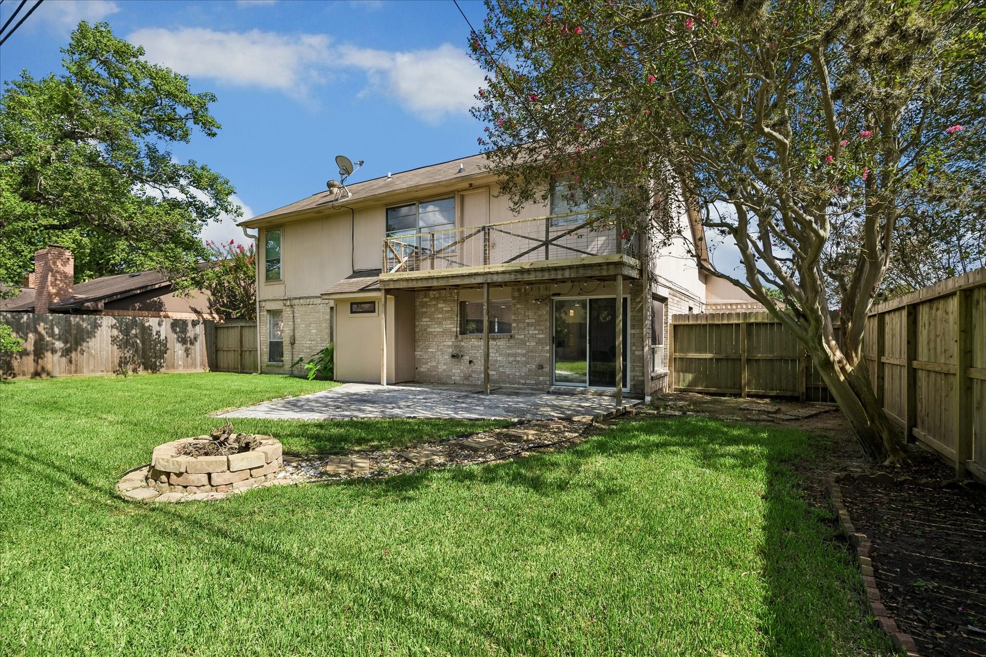 A balcony upstairs, patio just off the kitchen, and a fire pit ready for some cool fall nights. What a spacious yard!