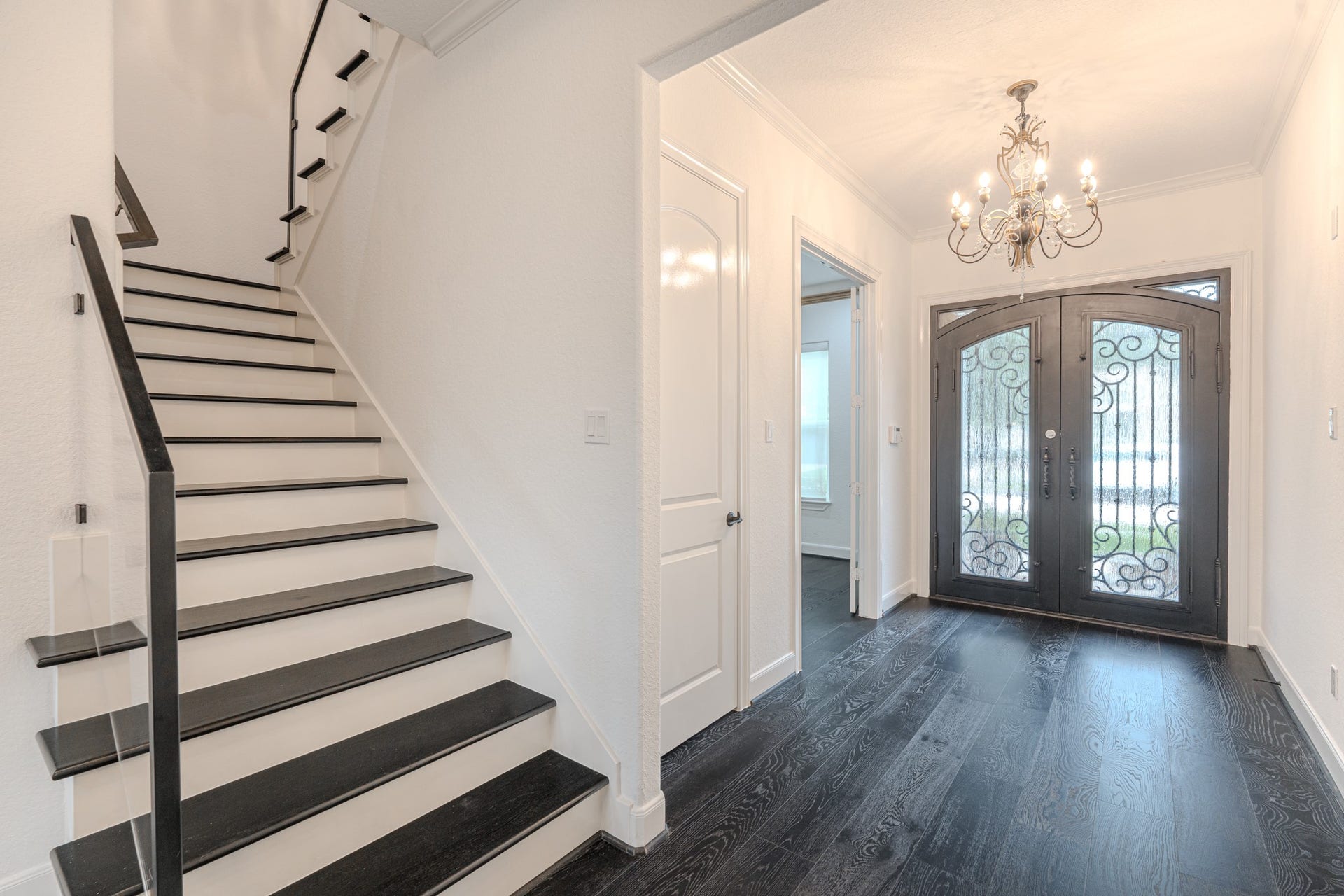 An elevated entry with decorative double iron doors, study/or home office separated in its own area off to the right in the front of the home. Coat closet for additional storage, and a glass railing leading you to the second floor with wood treads.