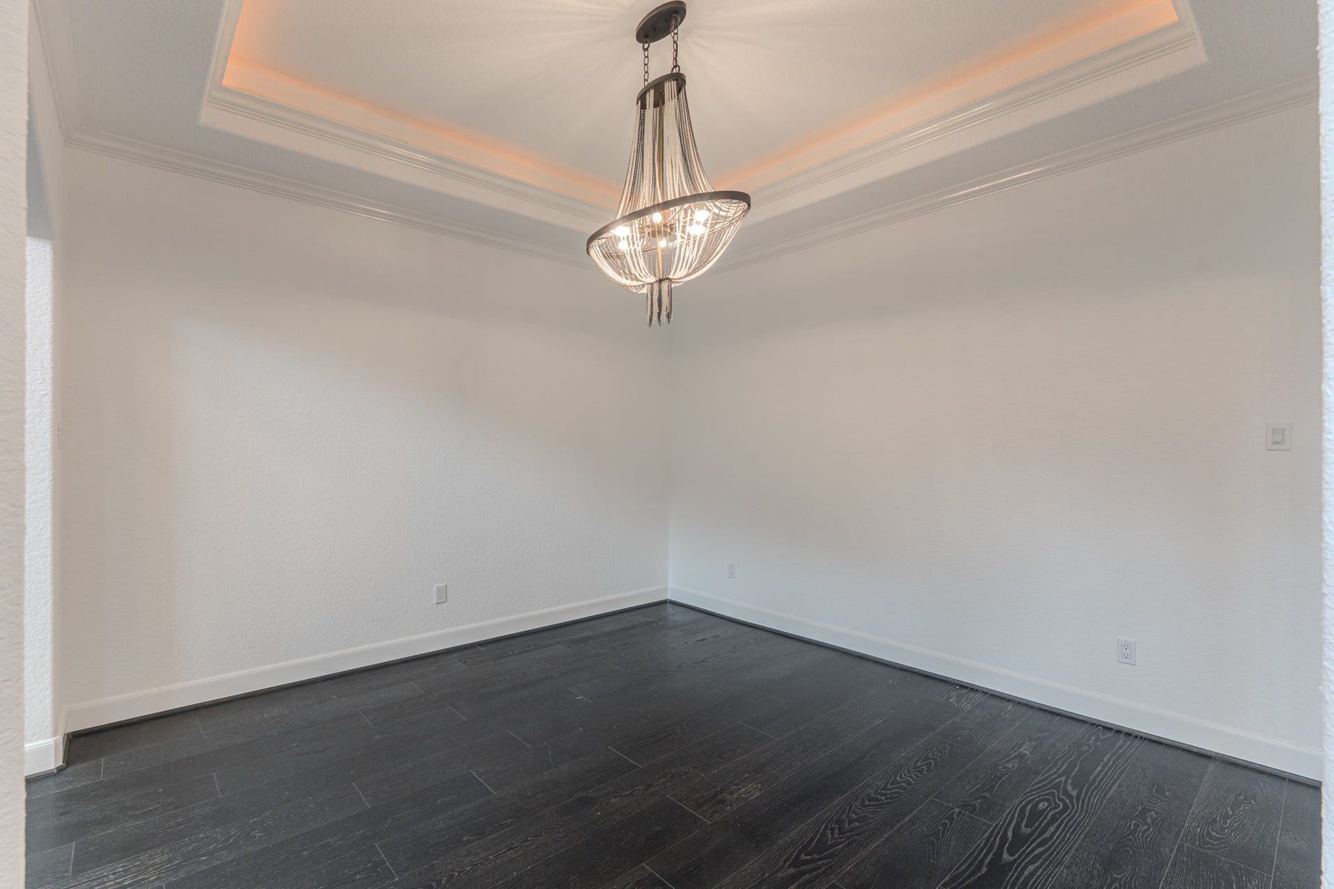 A elegant formal living room to host dinners. Chandelier is chic, crown molding, cove lighting, tray ceiling details and seamless engineered wood flooring.