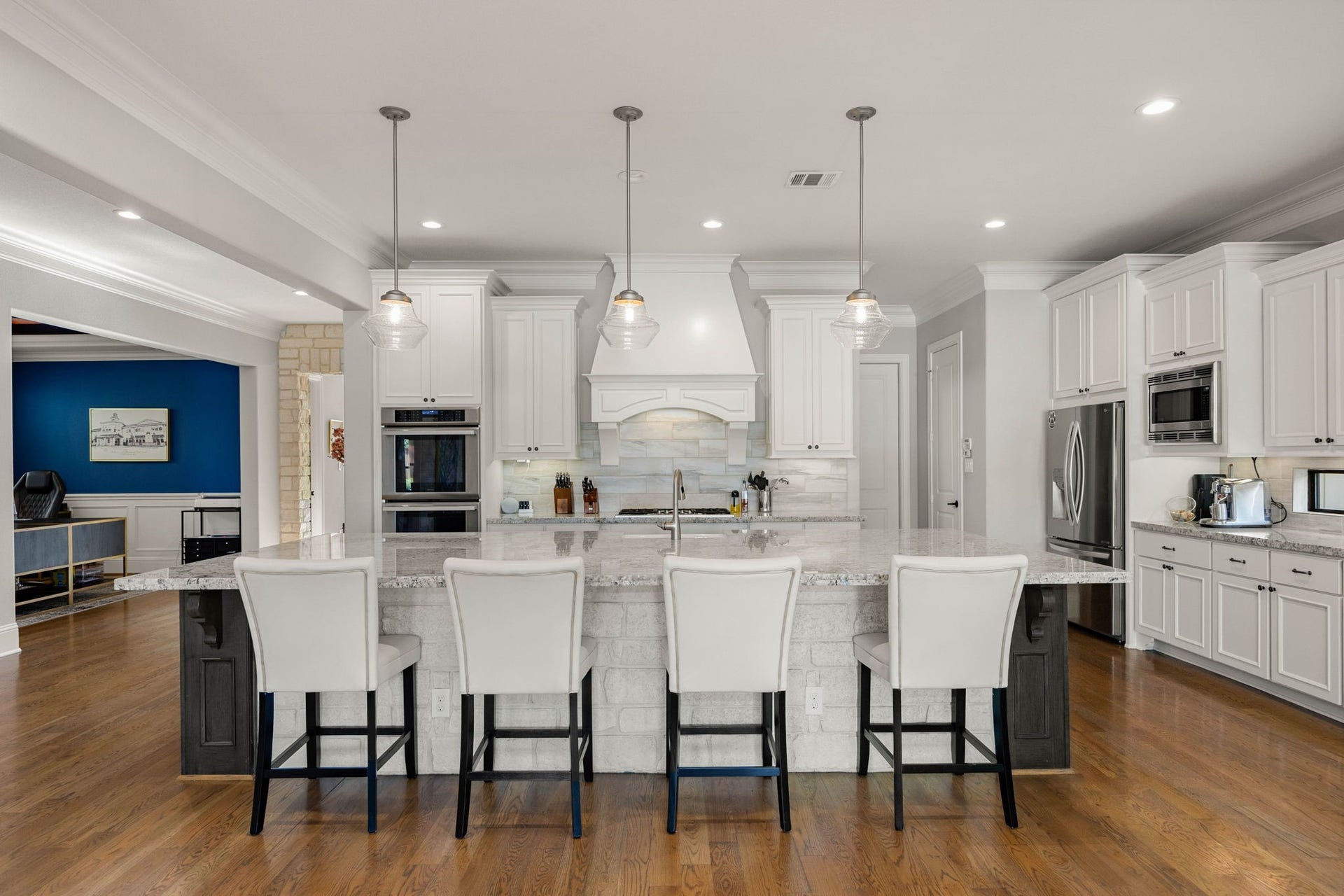 1847 Candlelight Place Drive, Houston, TX 77018 Spacious kitchen with custom white cabinetry, a large granite island with spaces for plenty of seating, and modern stainless steel appliances, perfect for cooking and entertaining.