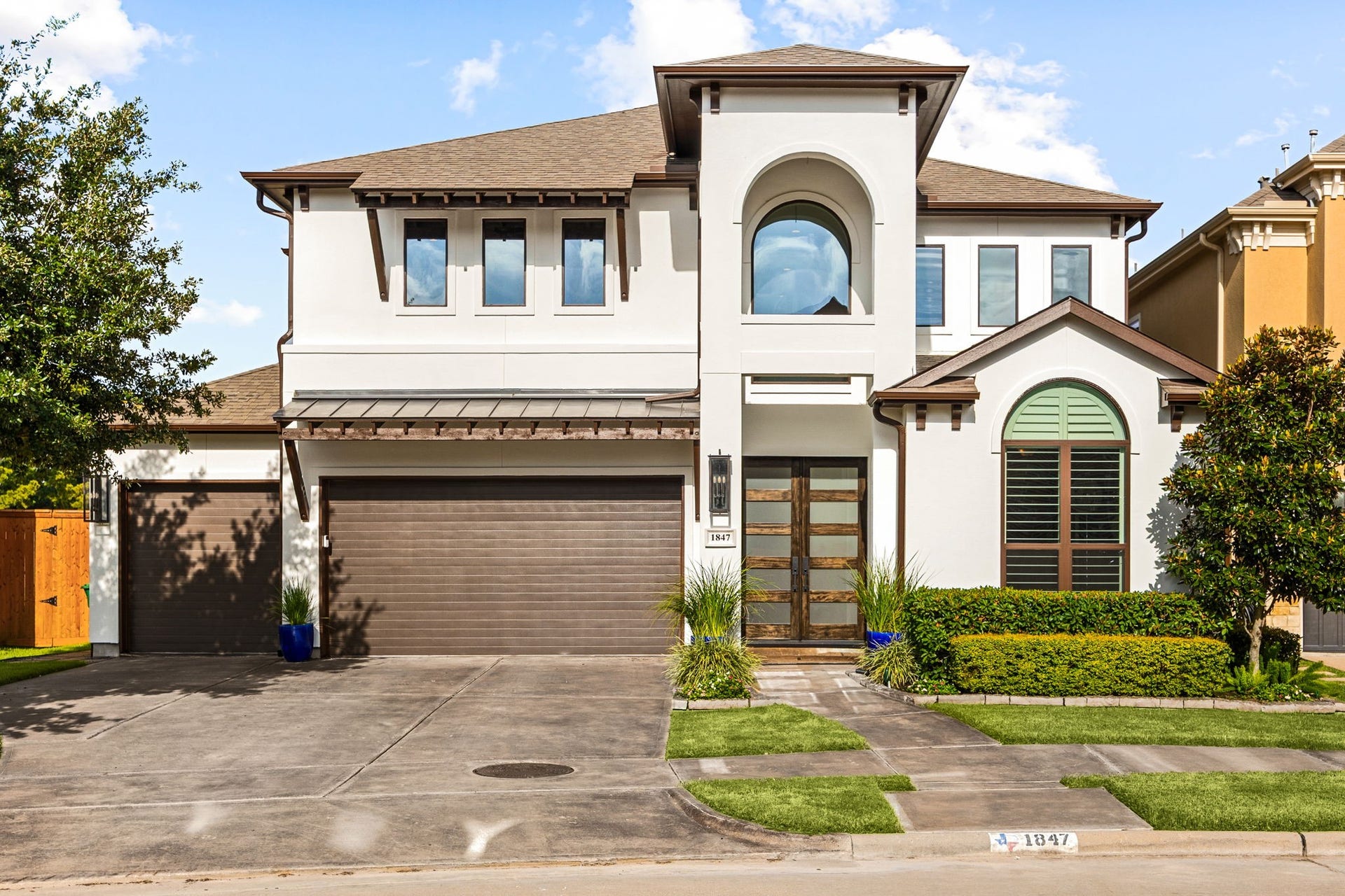 1847 Candlelight Place Drive, Houston, TX 77018 Modern two-story home with a sleek facade, featuring a spacious three car garage and double door front entry, surrounded by well-manicured landscaping & freshly painted exterior.
