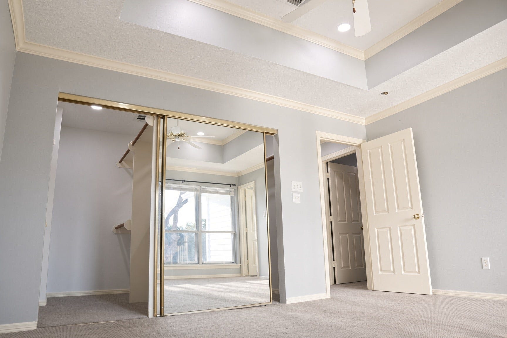 114 Oyster Creek Drive, Sugar Land, TX 77478 Spacious bedroom featuring elegant tray ceilings, mirrored sliding closet doors, and ample natural light from large windows, on the second level.