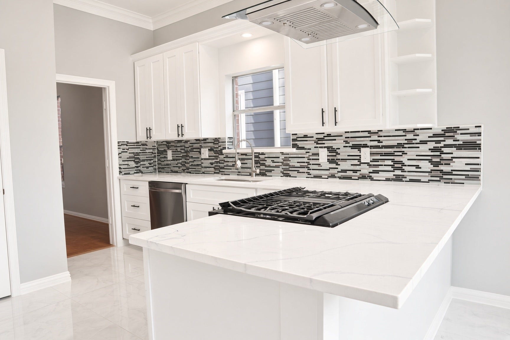114 Oyster Creek Drive, Sugar Land, TX 77478 Sleek kitchen featuring modern white cabinetry, a stylish black and white tile backsplash, and a spacious marble countertop with a built-in gas cooktop.