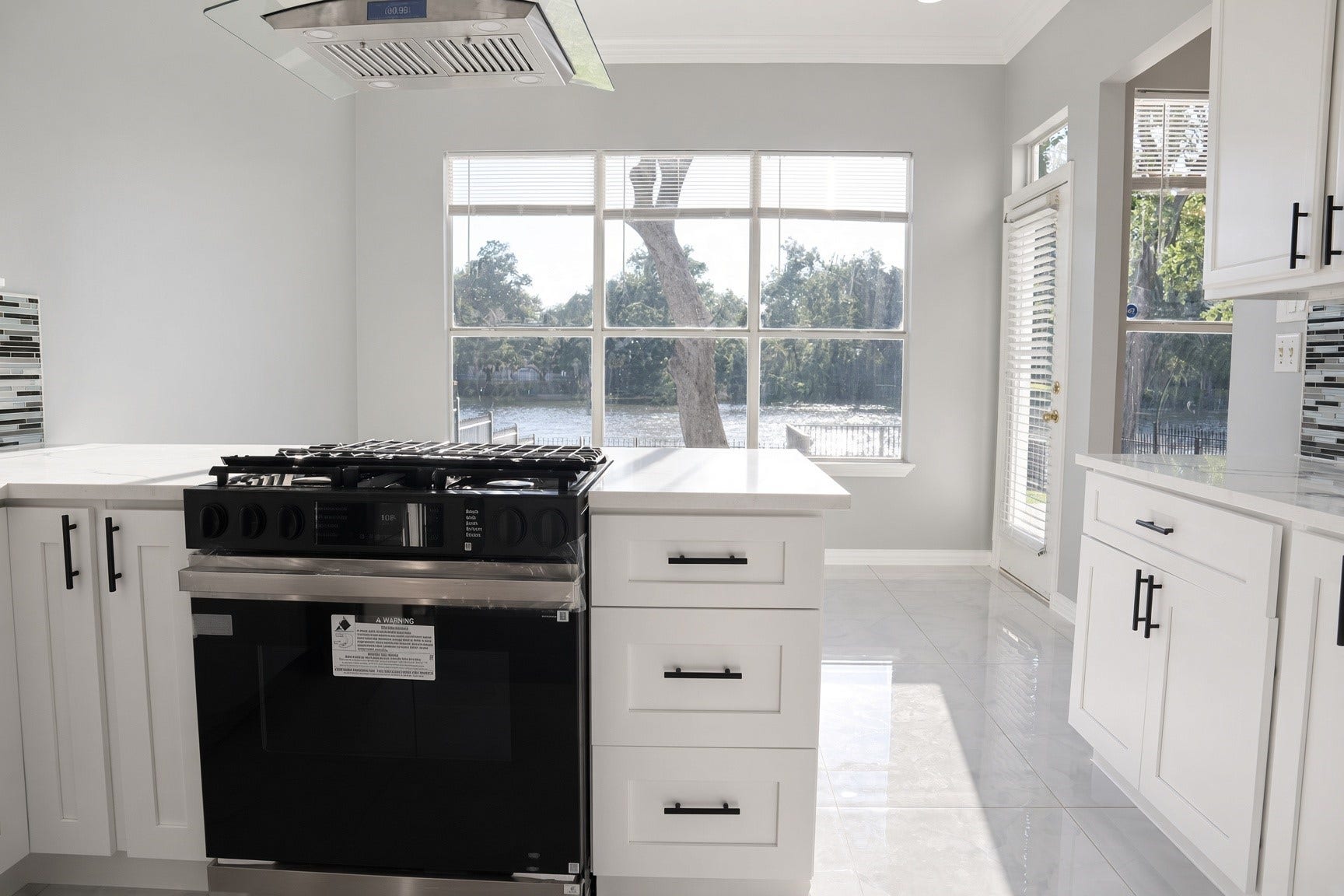 114 Oyster Creek Drive, Sugar Land, TX 77478 Bright kitchen with modern stainless steel appliances, sleek white cabinetry, and large windows offering scenic water views.
