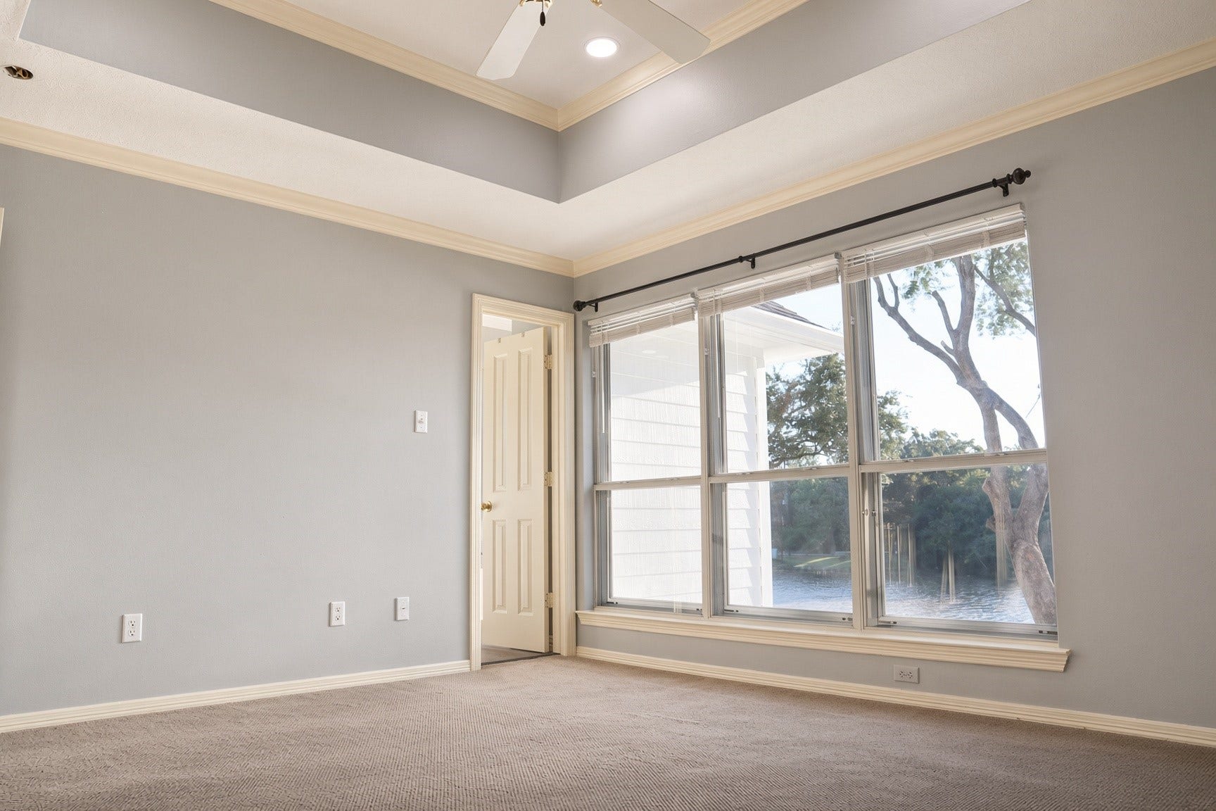 114 Oyster Creek Drive, Sugar Land, TX 77478 Bright and inviting room with large windows offering serene views, overlooking the water complemented by a stylish tray ceiling and soft carpeting.