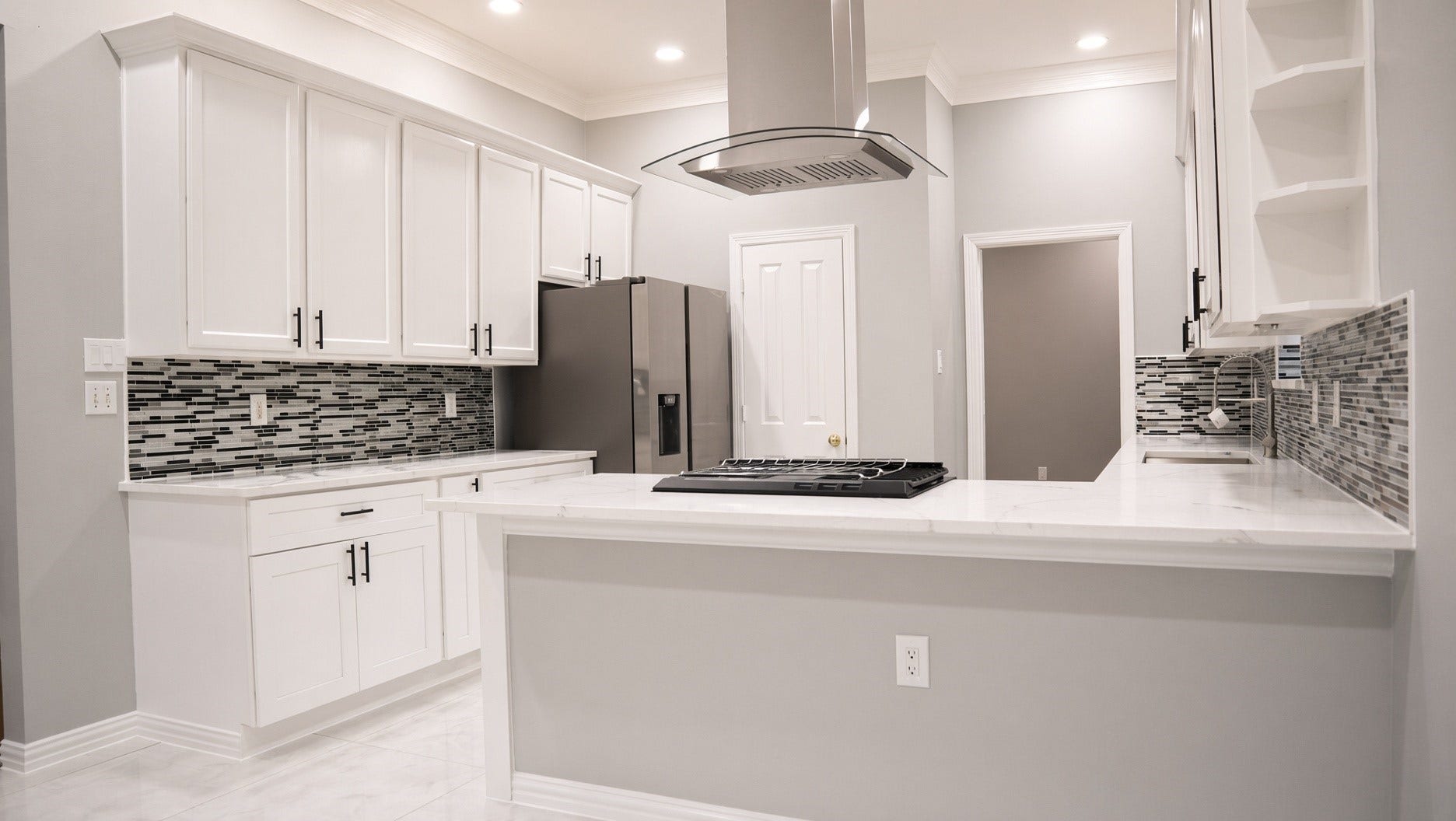 114 Oyster Creek Drive, Sugar Land, TX 77478 Brand new, Modern kitchen with sleek white cabinetry, stainless steel appliances, and a stylish tile backsplash. The open layout features a central island with a cooktop and contemporary range hood, perfect for cooking and entertaining.